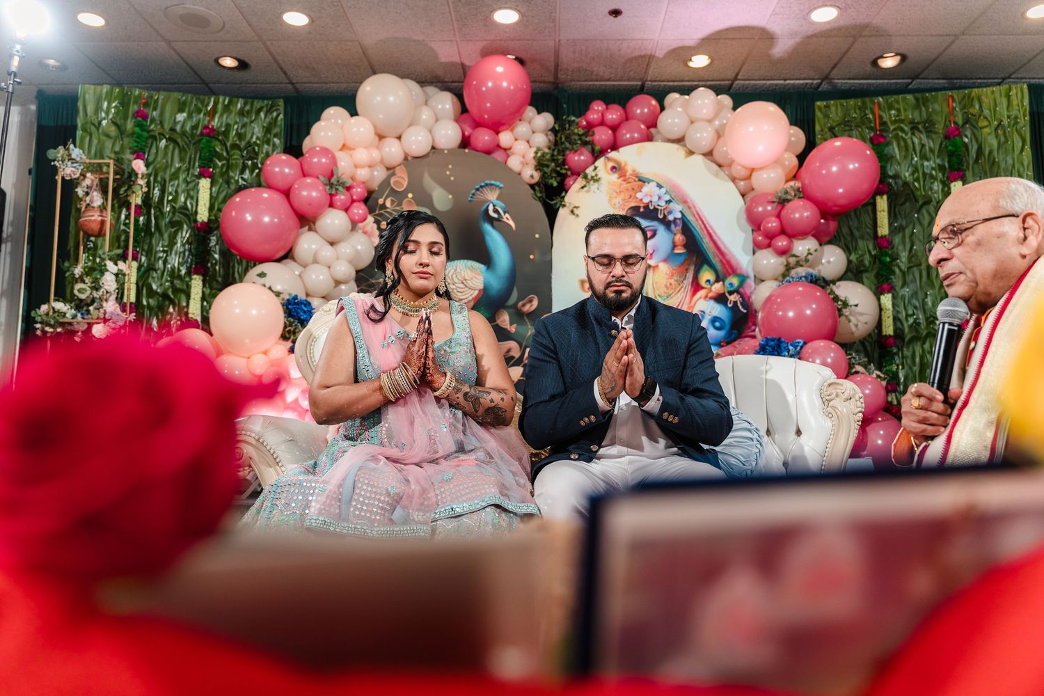 Couple performs ceremony under balloon arch with pink and white decorations.