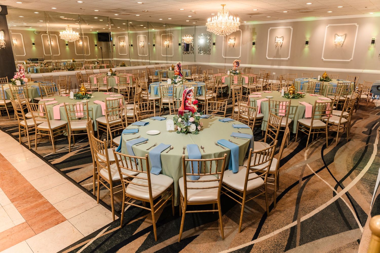 Elegant ballroom setup with gold chairs and blue tablecloths arranged in circular formation.