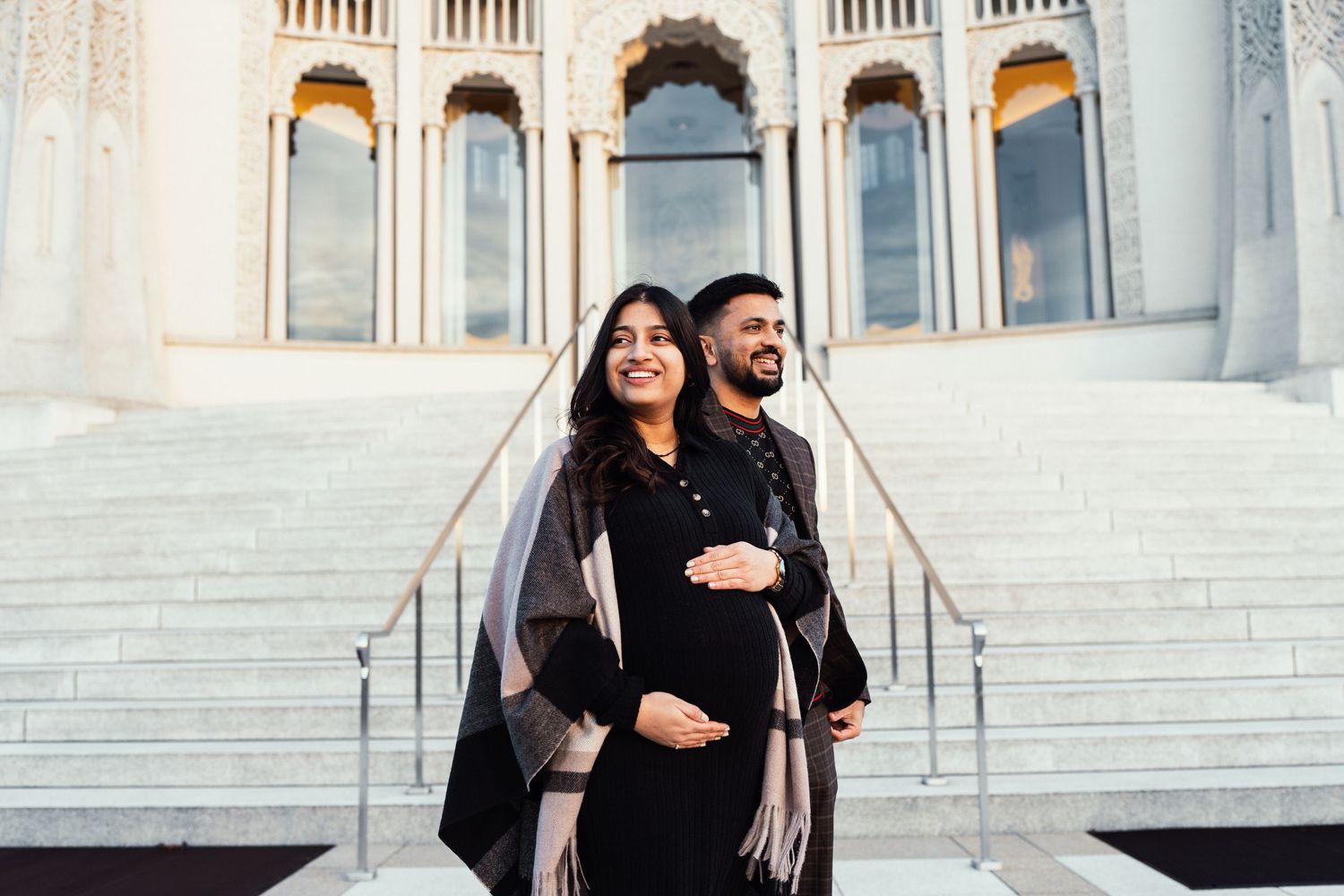 A couple embracing on grand marble steps of a classical building.