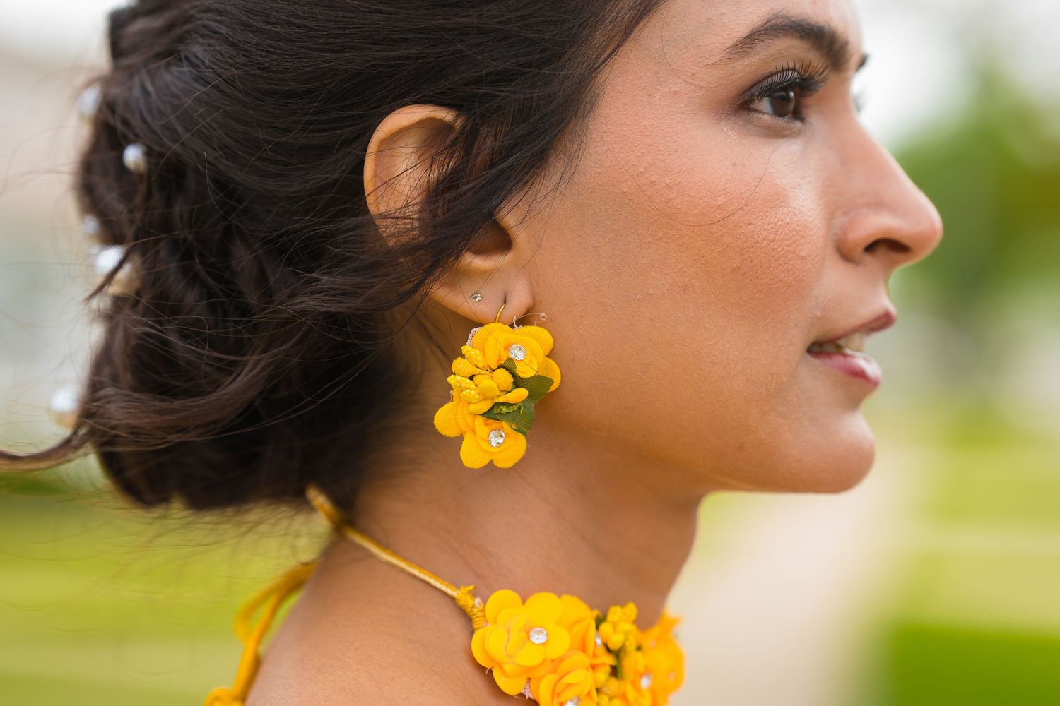 Side profile showing traditional Indian yellow floral jewelry and updo hairstyle.