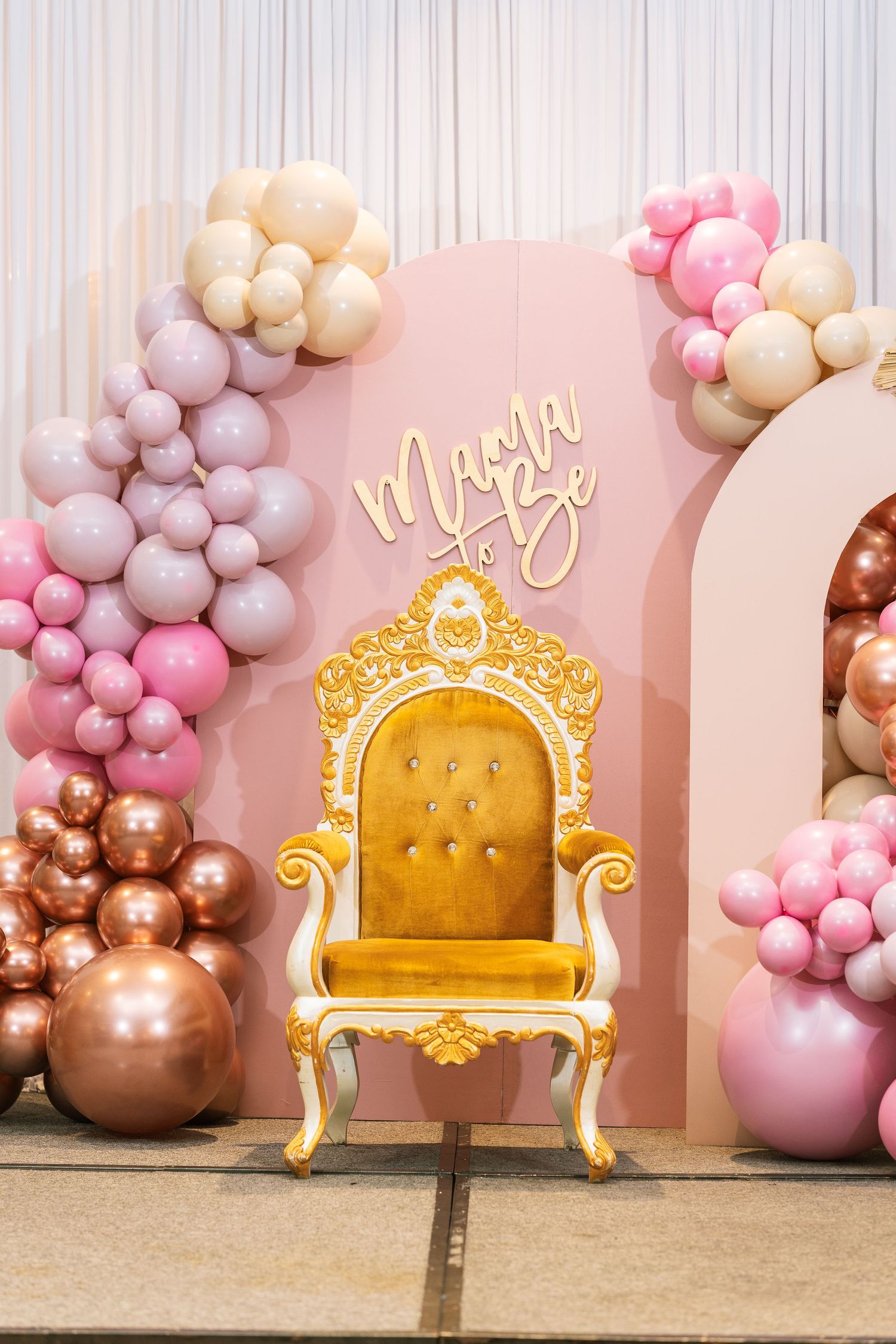 Elegant gold throne chair with pink and rose gold balloon garlands against a blush pink backdrop.