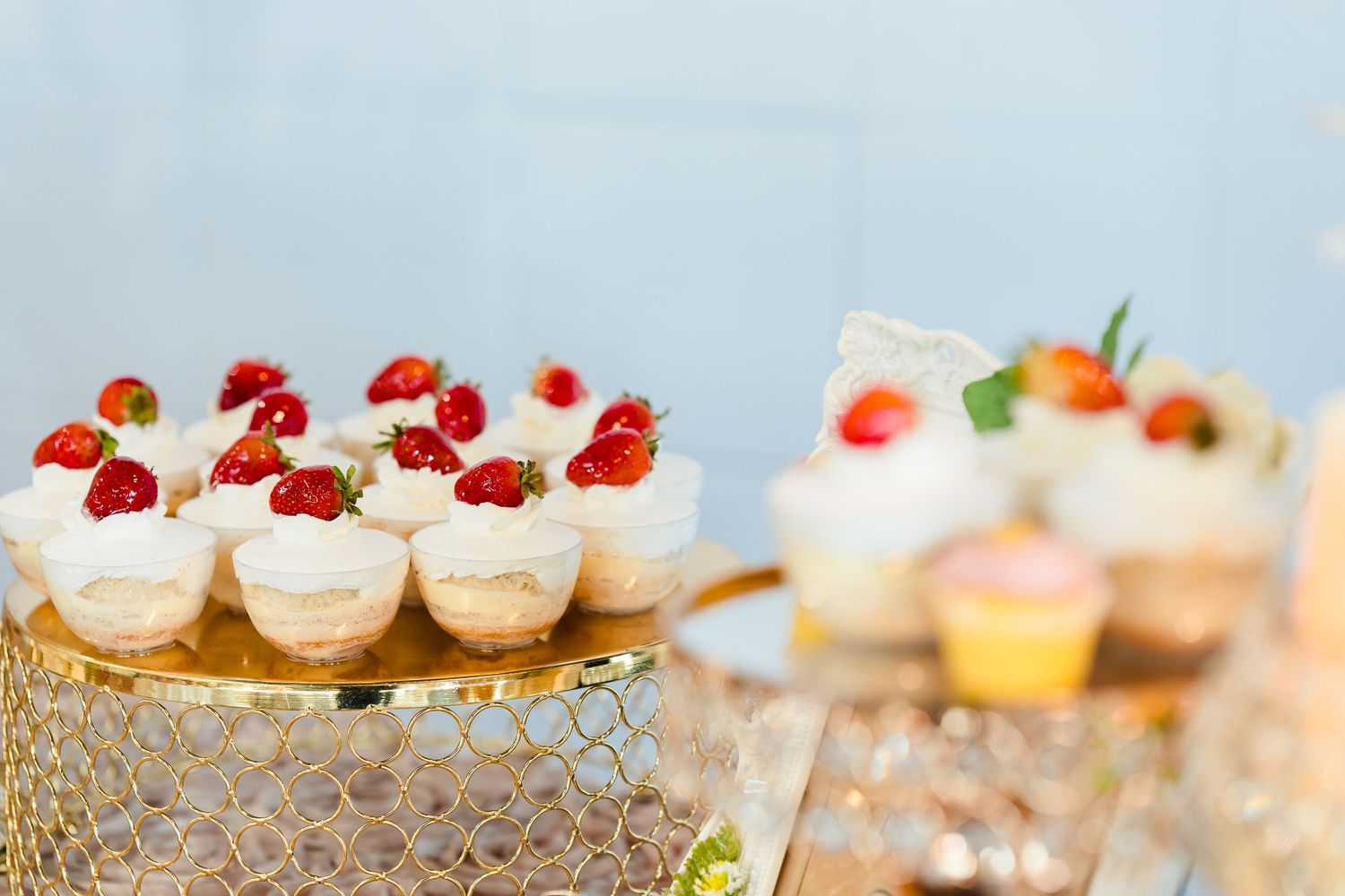 Delicate cupcakes topped with fresh strawberries displayed on a crystal dessert stand.