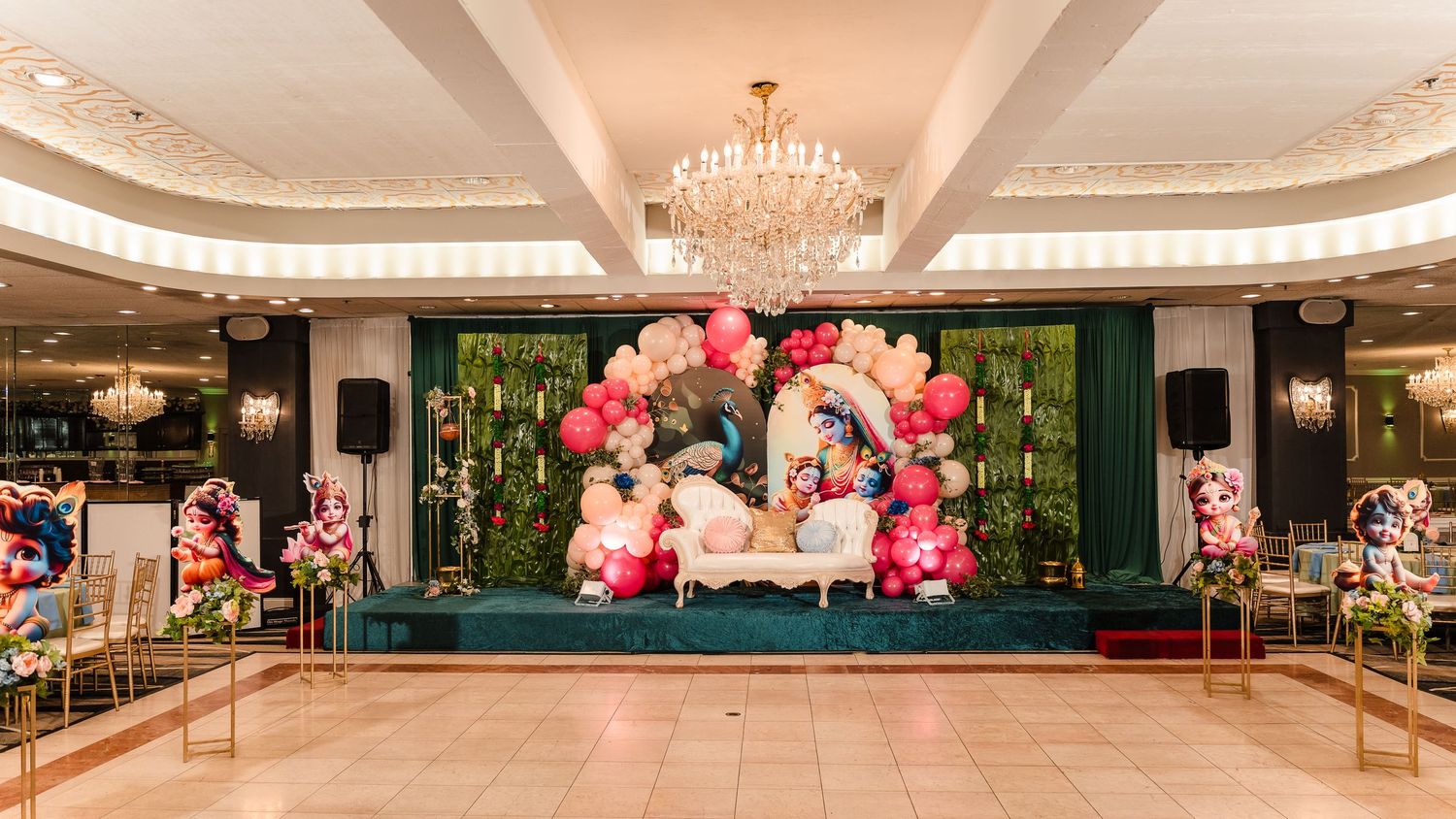 Grand ballroom decorated with pink balloon garlands and elegant stage setup for special occasion.