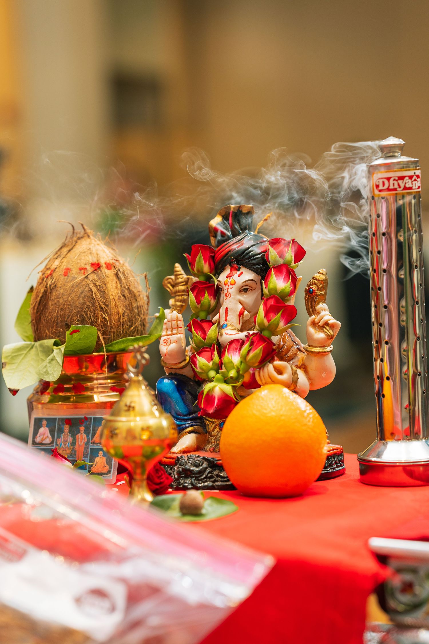 Colorful Indian ceremonial display with incense smoke and decorative Ganesh figurine.