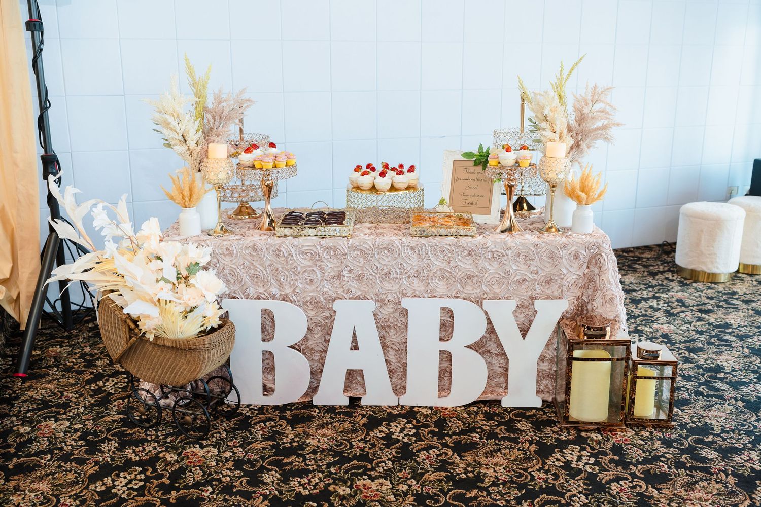 Baby shower dessert table with neutral decor, lanterns and BABY letters in front.