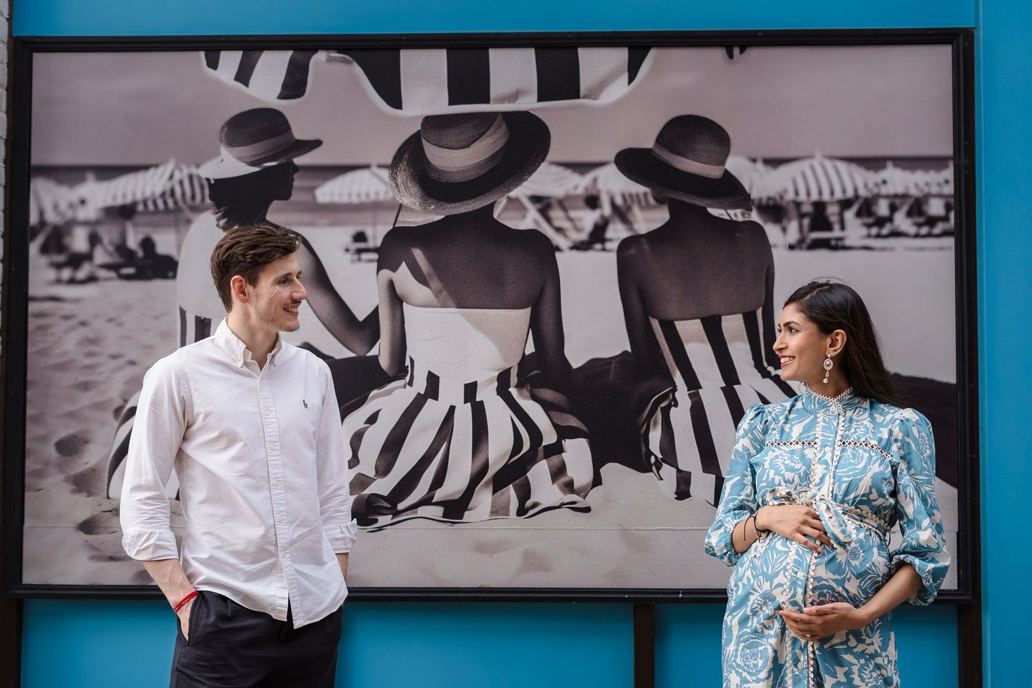A couple stands in conversation against a wall with black and white zebra-themed artwork in the background.