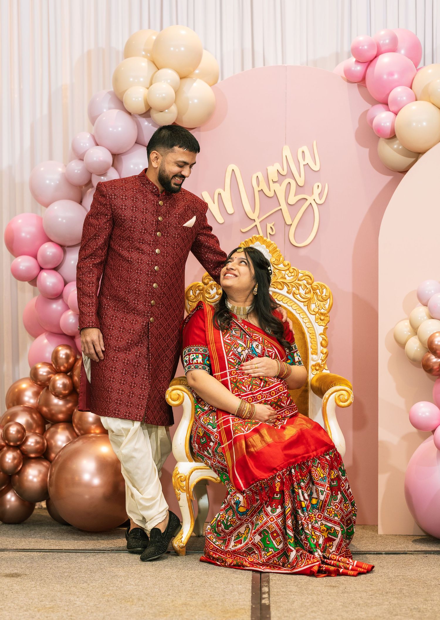 Traditional Indian maternity photoshoot setup with elegant balloon decorations and golden throne.