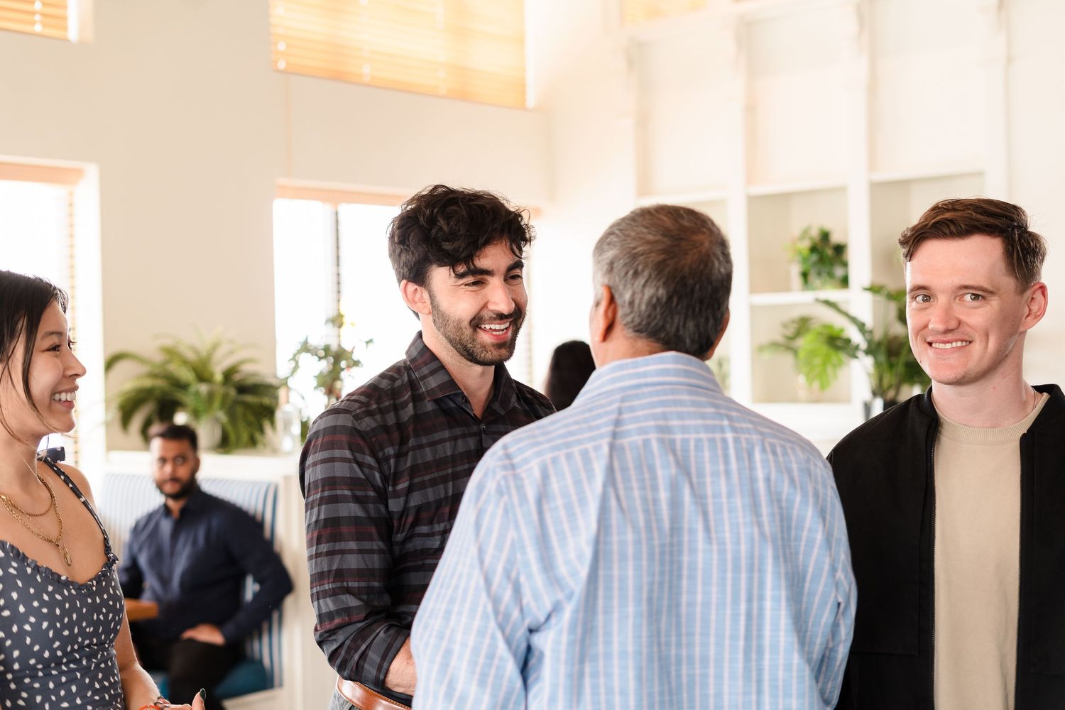Group of people having an animated conversation in a bright modern office space.