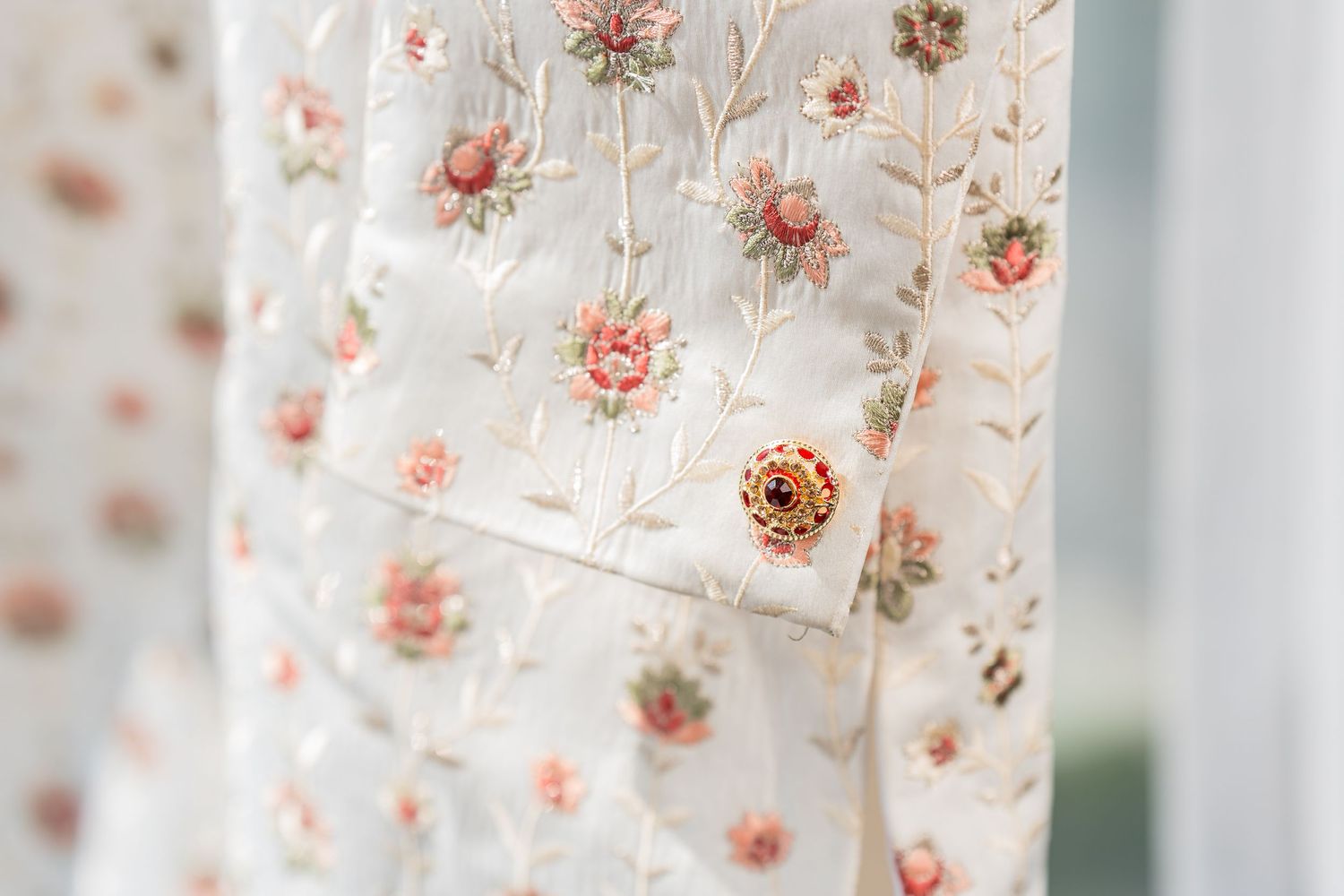 Delicate floral print fabric with pink roses and a gold button detail.