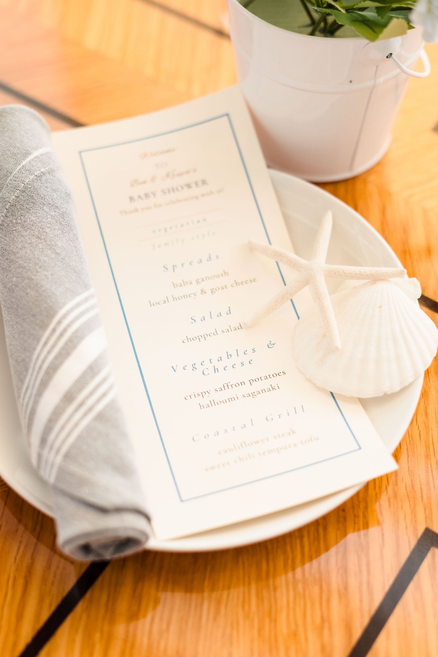 Elegant place setting with white napkin, menu card and starfish decoration on wooden table surface.