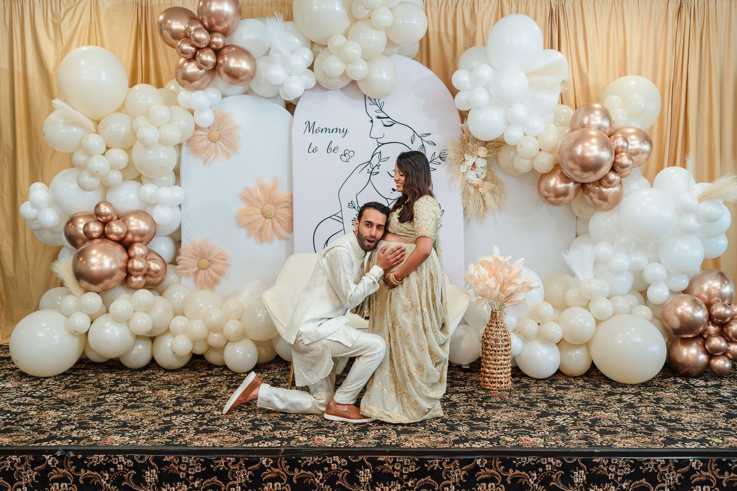 Festive balloon arch display with rose gold and white balloons against a champagne backdrop.