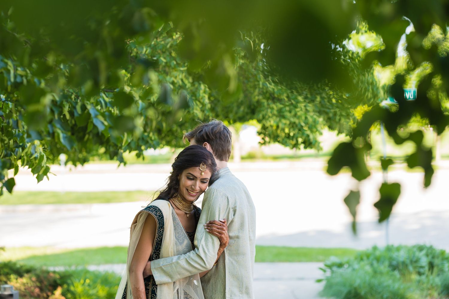 Romantic couple sharing intimate moment under tree branches in garden setting.