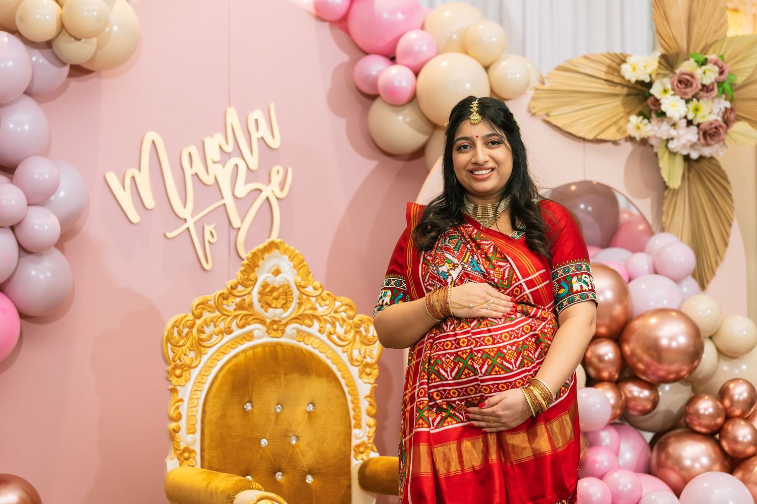 Beautifully decorated maternity photo backdrop with pink balloons and gold accent pieces.