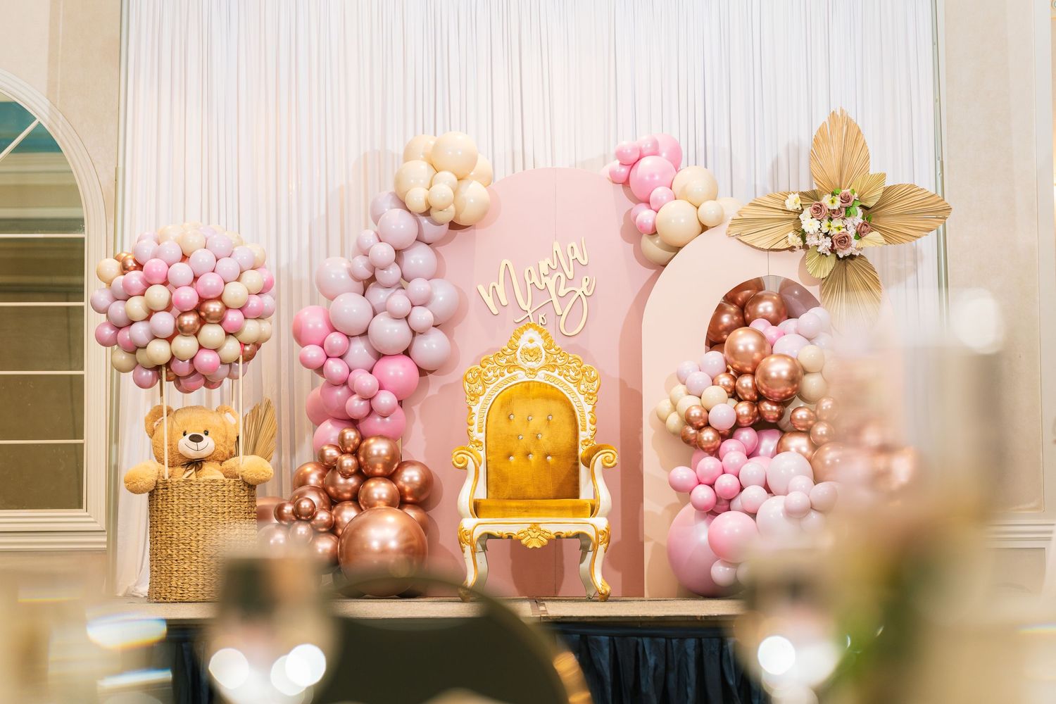 Decorative photo backdrop featuring golden throne and pink balloon garlands.