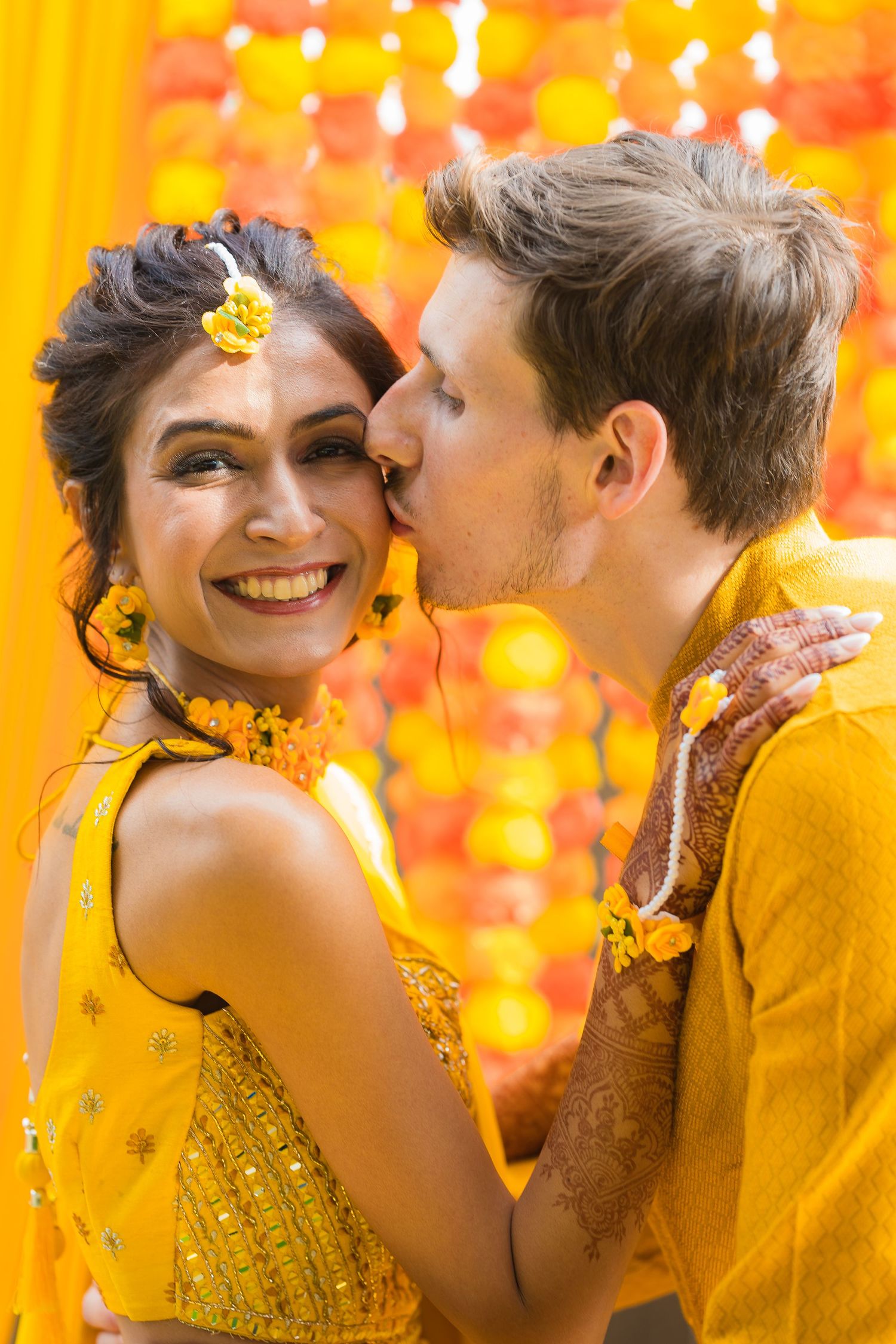 A loving couple embraces against festive yellow and orange decorations during their celebration.