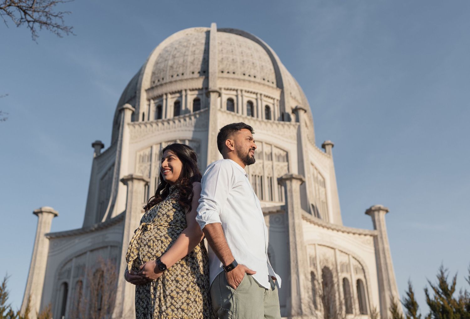 Couple poses against grand Baha'i Temple architecture during outdoor photoshoot.