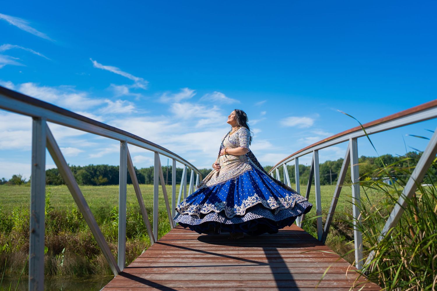 Traditional dress spinning motion captured on wooden bridge with blue sky background.