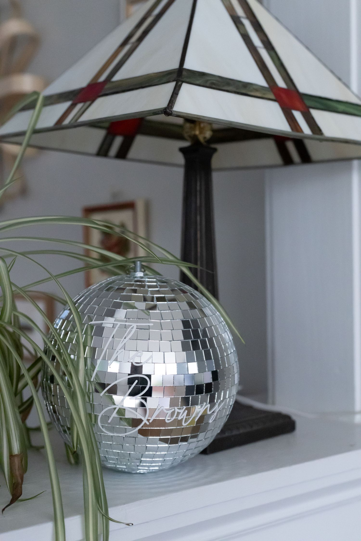 A disco ball sitting in front of a stained-glass lamp