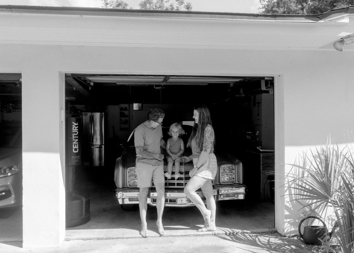 Black and white photo of a family gathered in a garage around a vintage truck.