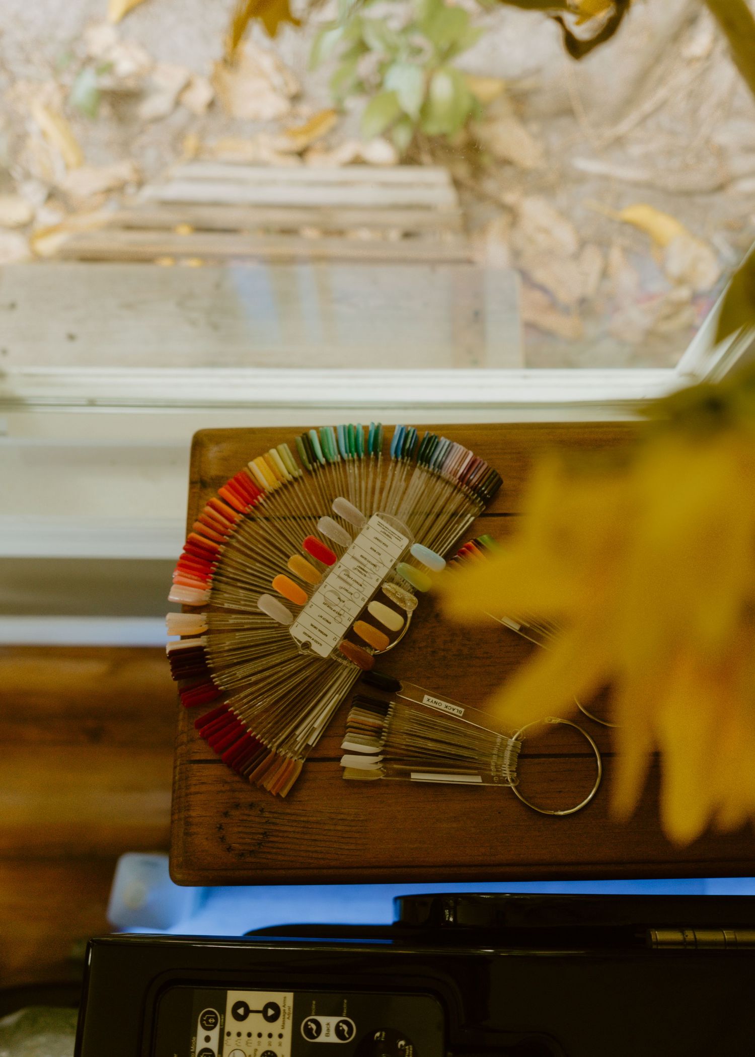 Colorful thread color swatch fan displayed on a wooden board near a window with autumn leaves outside.