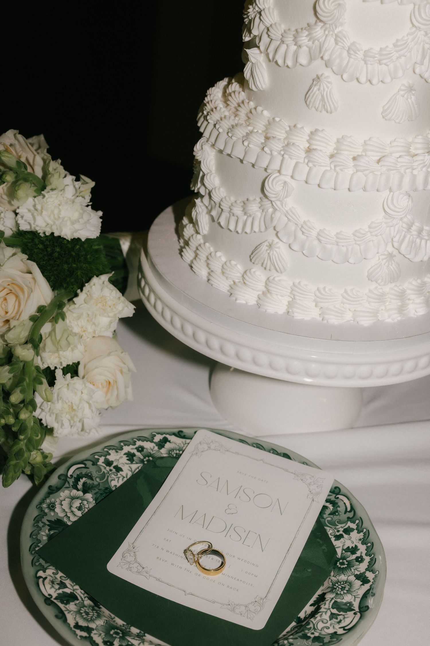 Wedding cake details with white frosting and gold wedding rings displayed on green decorative plates.