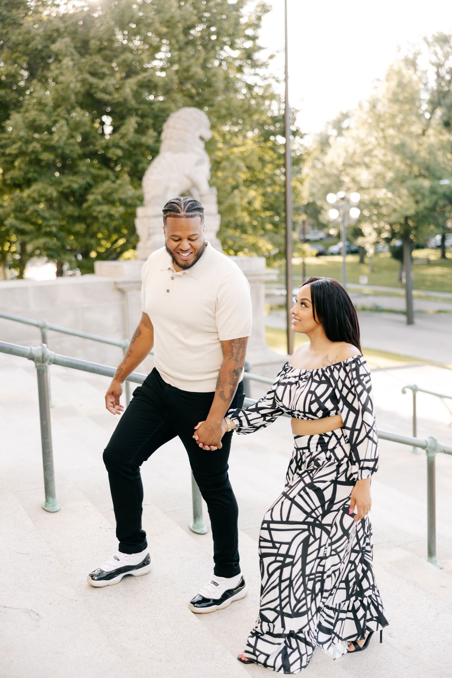 A couple shares a playful moment on outdoor stairs wearing contrasting black and white outfits.
