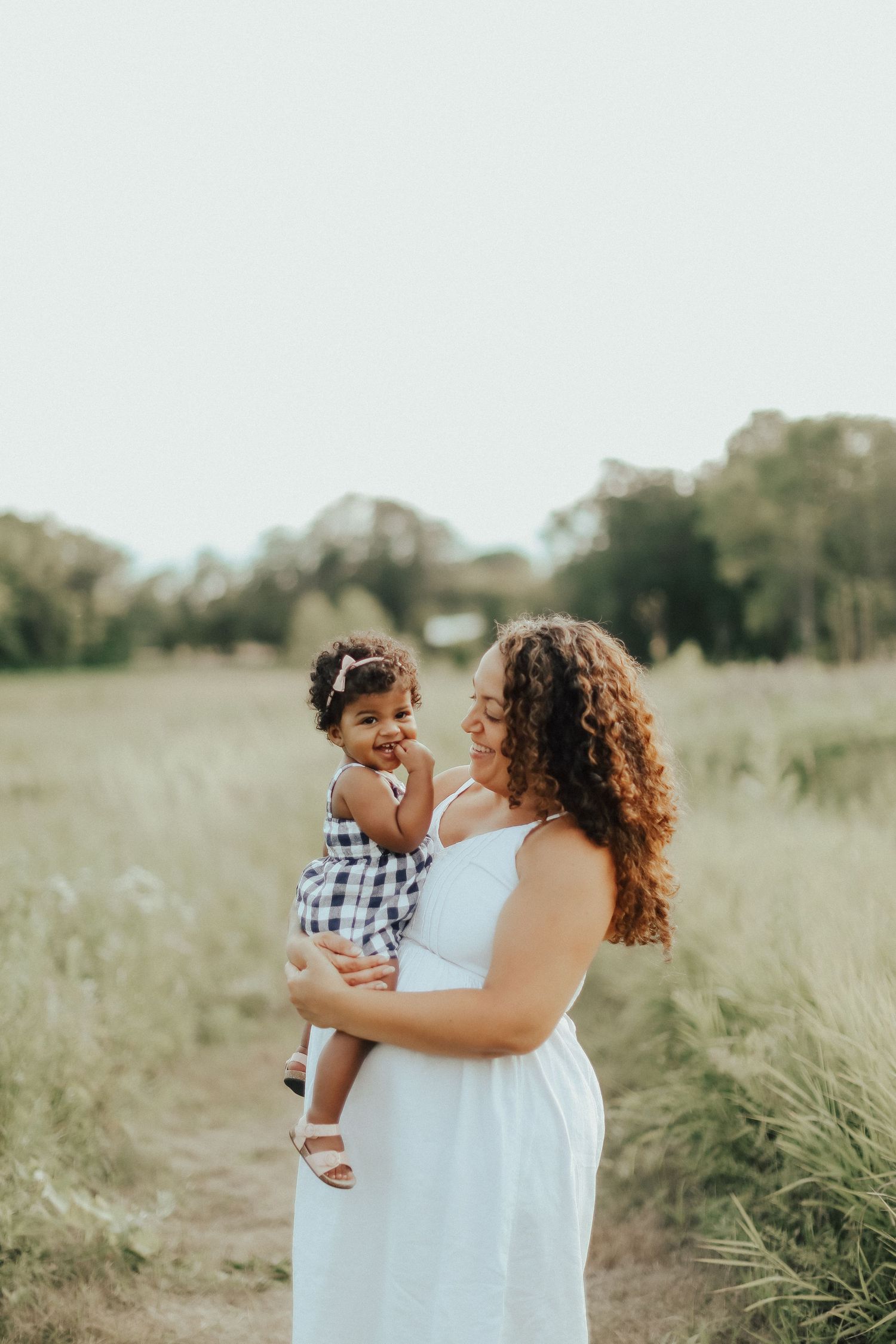 A tender moment between parent and child laughing together in a sunlit meadow.