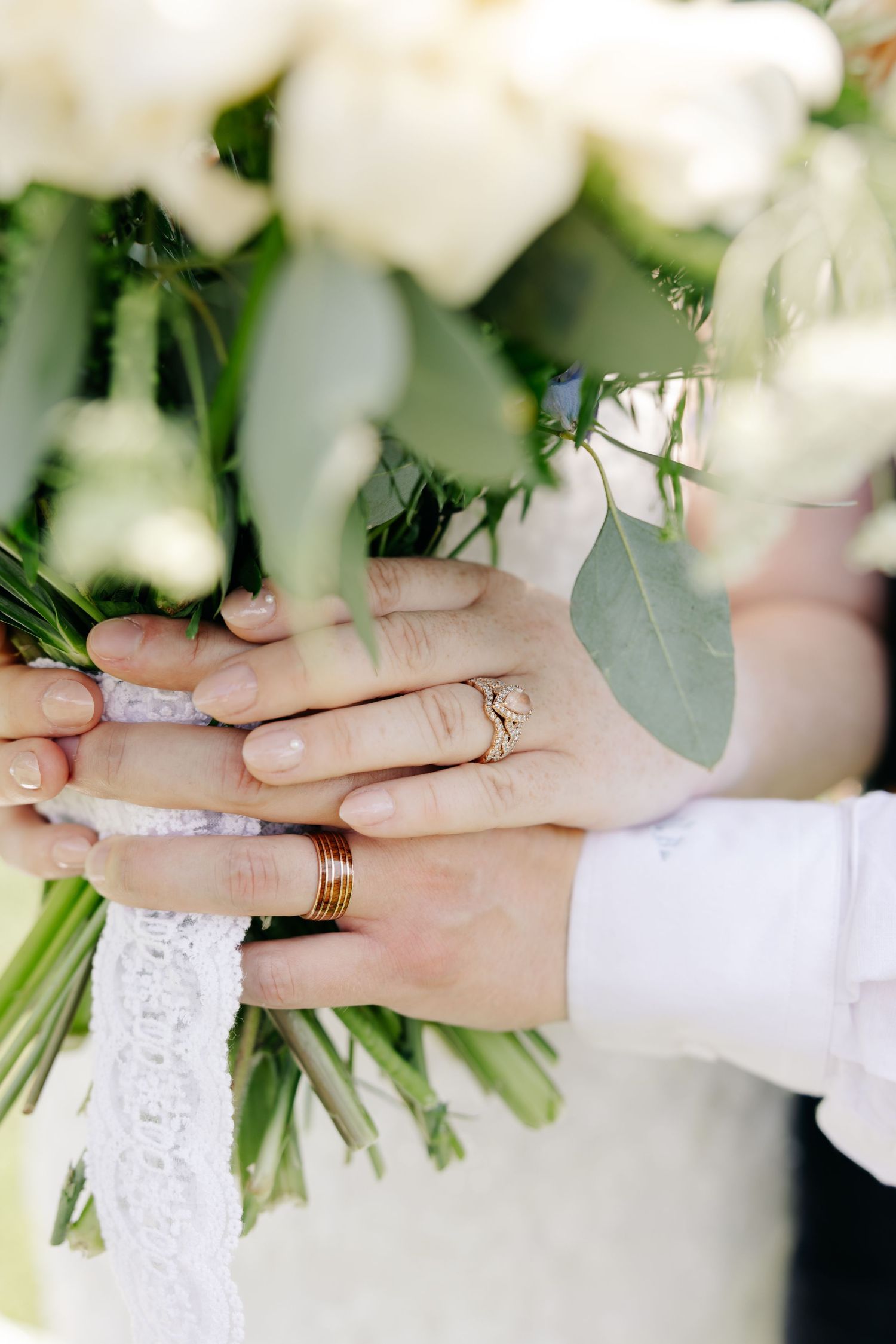 Close-up sequence of wedding rings being exchanged during a ceremony with white flowers in the background.