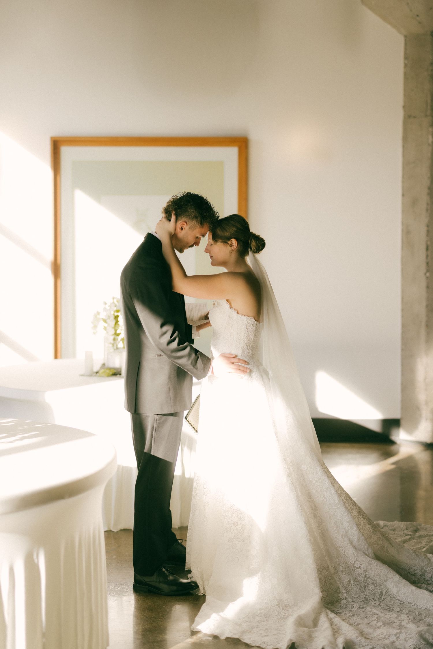 A romantic wedding couple embraces in soft natural window light creating an ethereal series of dance-like poses.