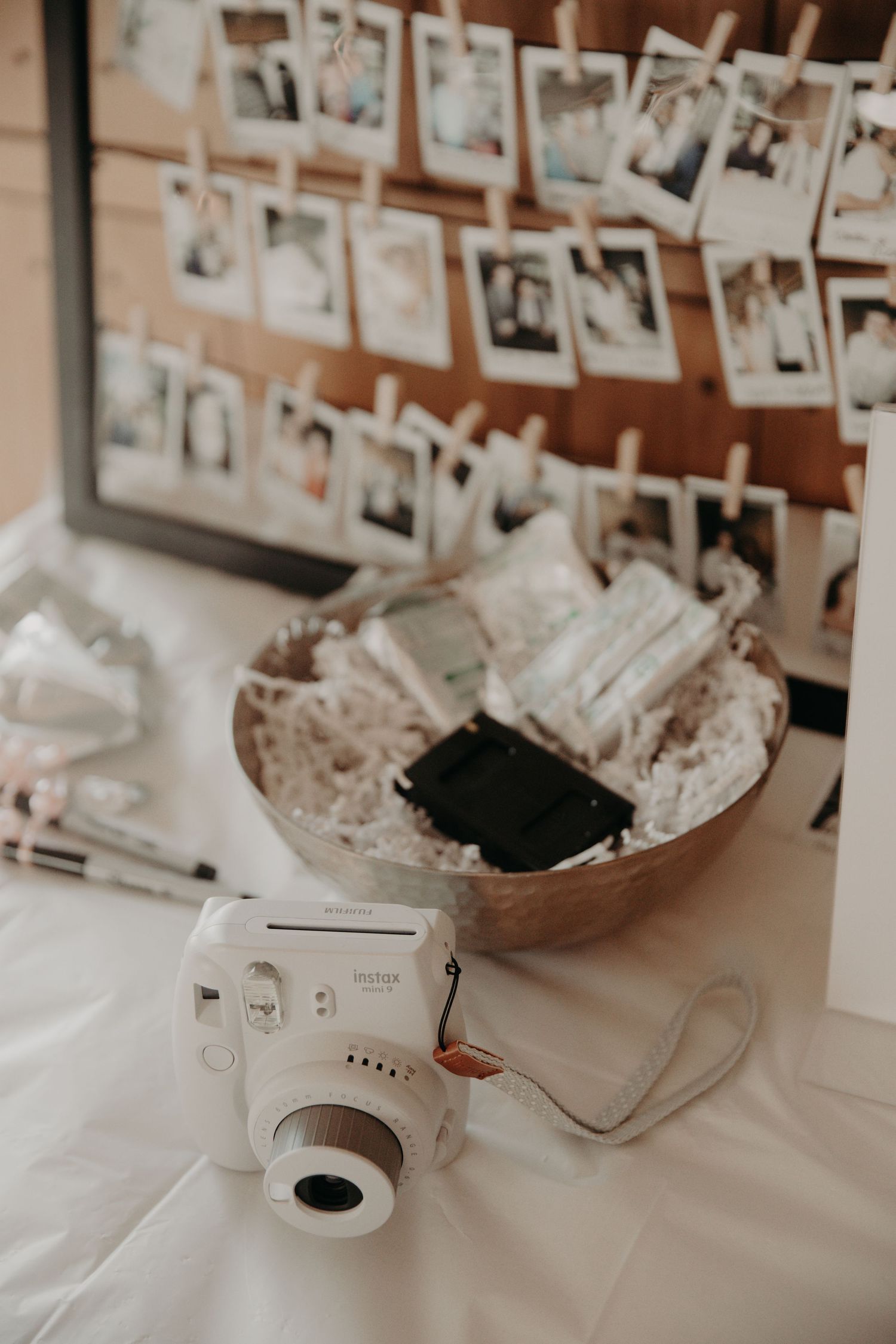 Polaroid photo display with instant camera and decorative bowl at wedding reception.