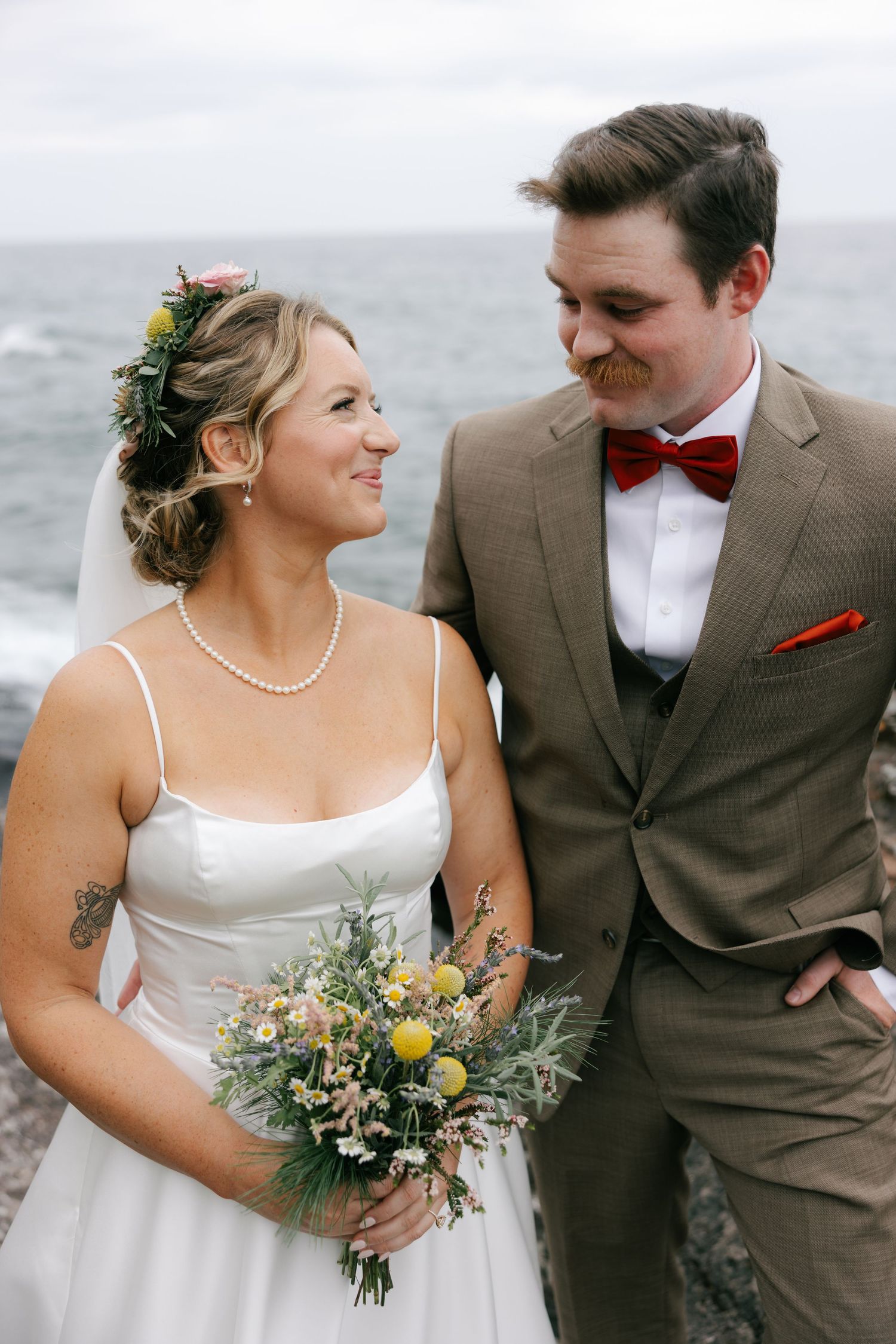 A wedding couple shares intimate moments by the ocean in a series of romantic portraits.