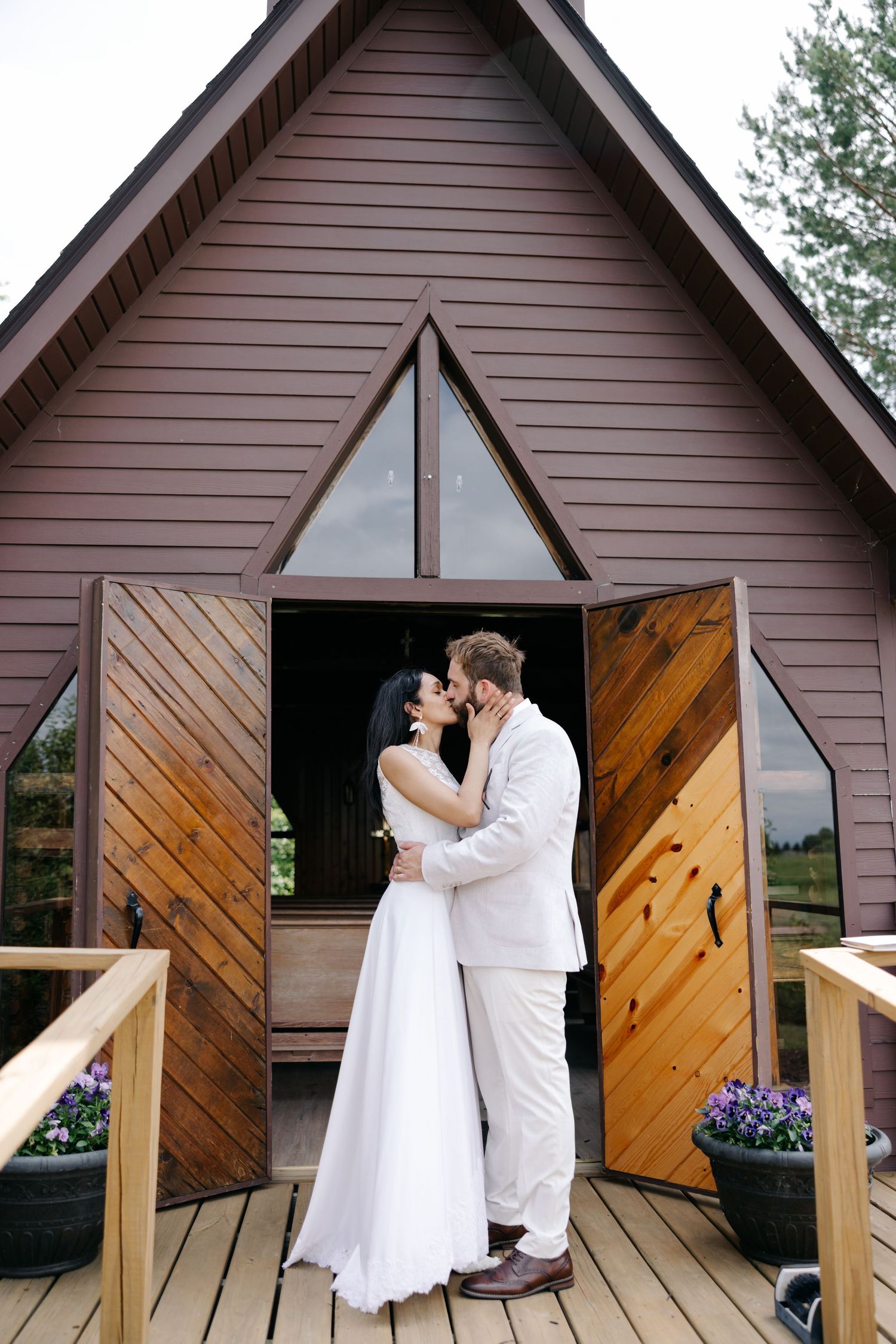 A series of wedding photos showing a couple in white attire sharing intimate moments on a rustic wooden deck of a chapel.