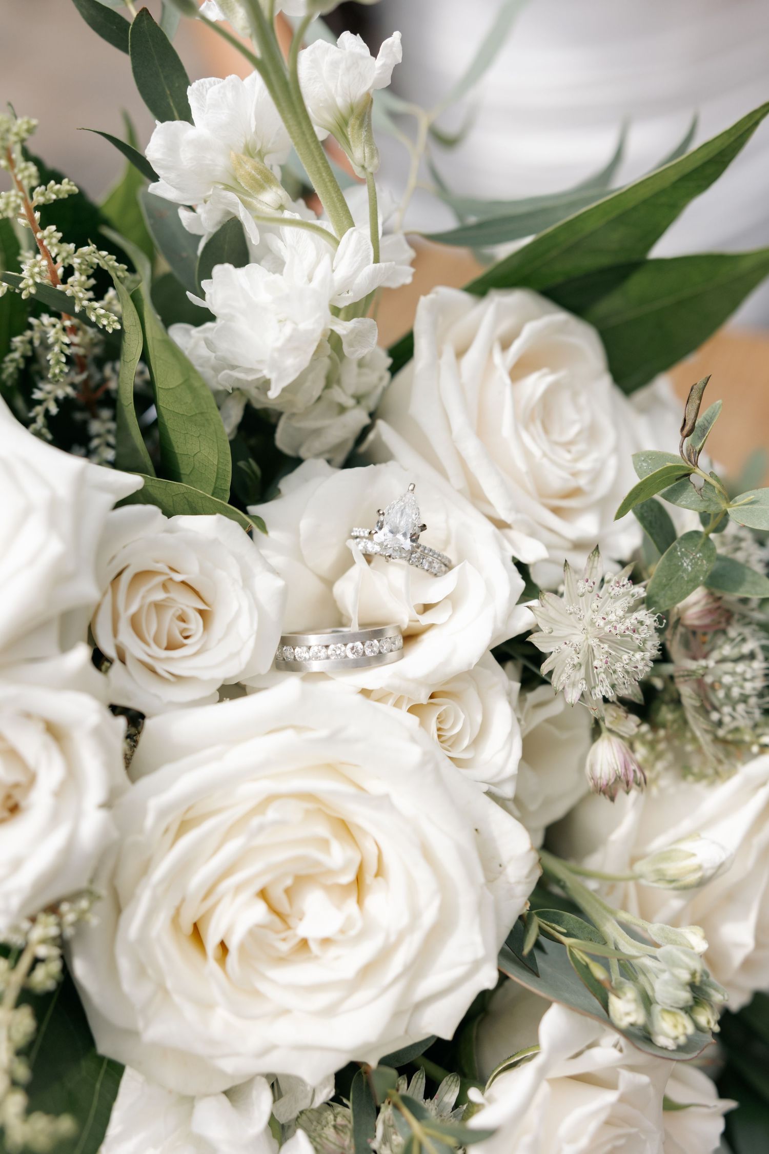 Elegant white rose and greenery wedding bouquet arrangement with delicate baby's breath accents and glossy leaves.