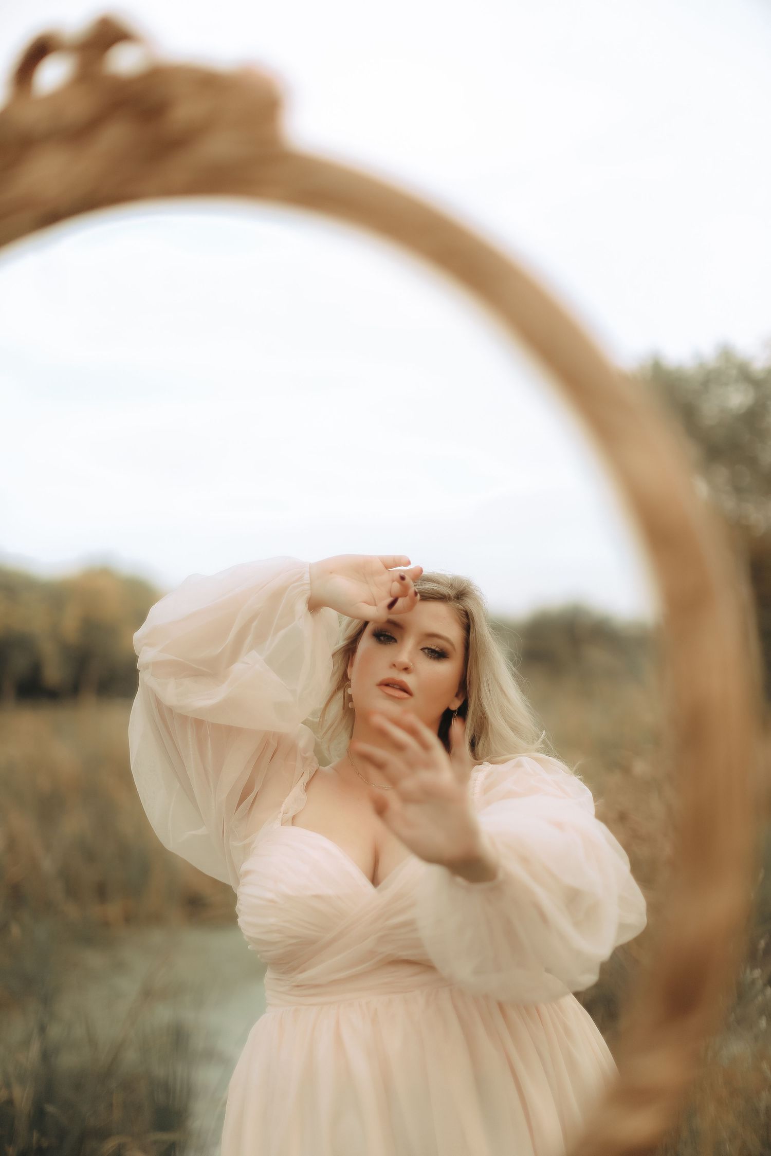 A ethereal portrait of a person in a flowing white dress against a dreamy natural backdrop.