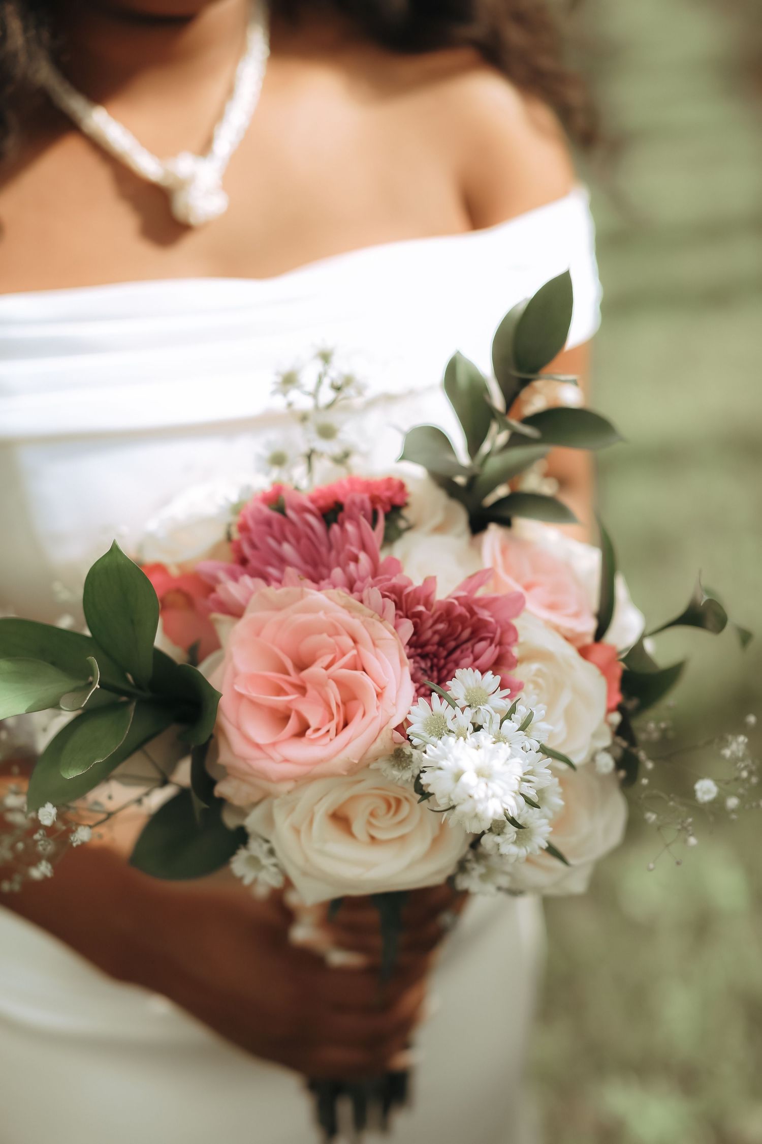 Close-up of bridal bouquet with pink roses, white flowers and greenery.