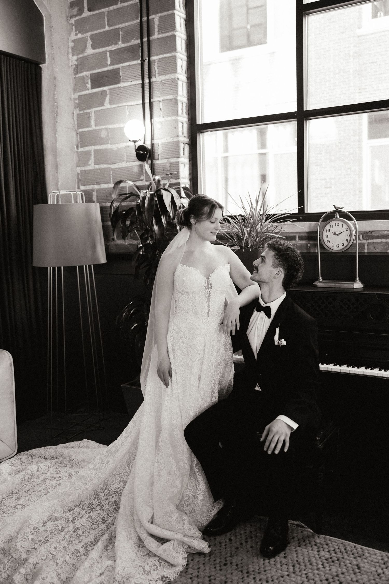 A romantic black and white photo series of a couple in wedding attire dancing together in an elegant room with brick walls.