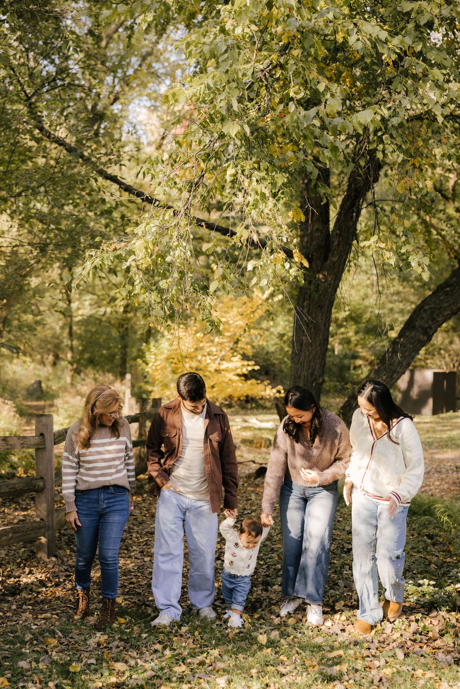 People gather in a wooded area with fallen leaves during an autumn photo shoot outdoors.