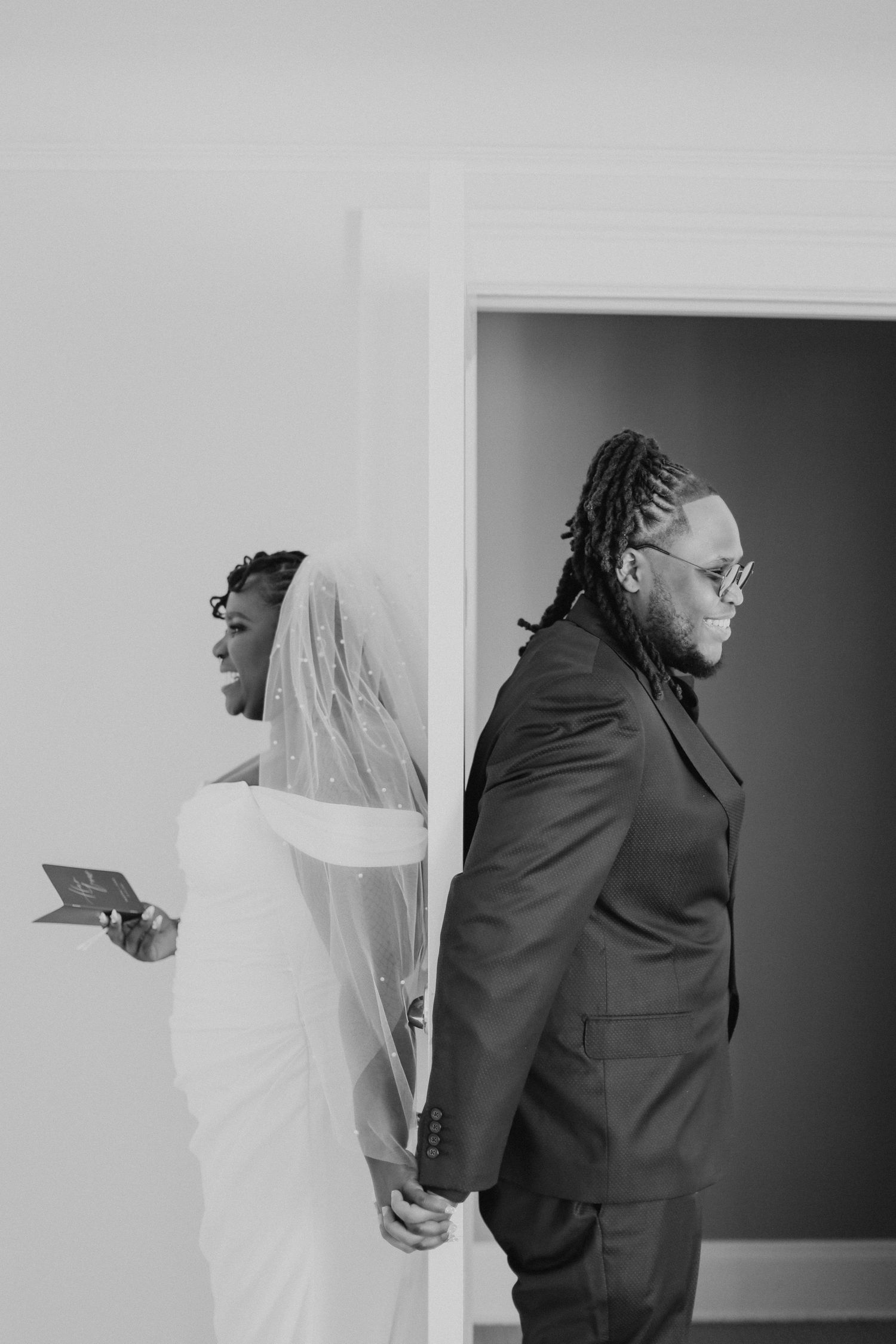 A couple holds hands during their first look, separated by a wall.