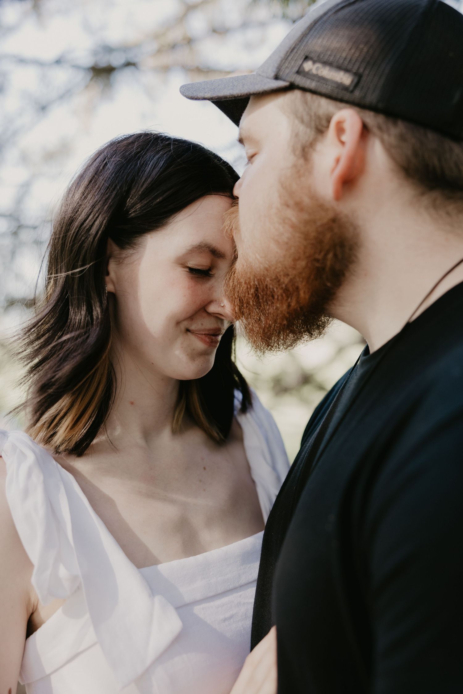 A tender intimate moment between two people sharing a gentle embrace outdoors during a photo session.