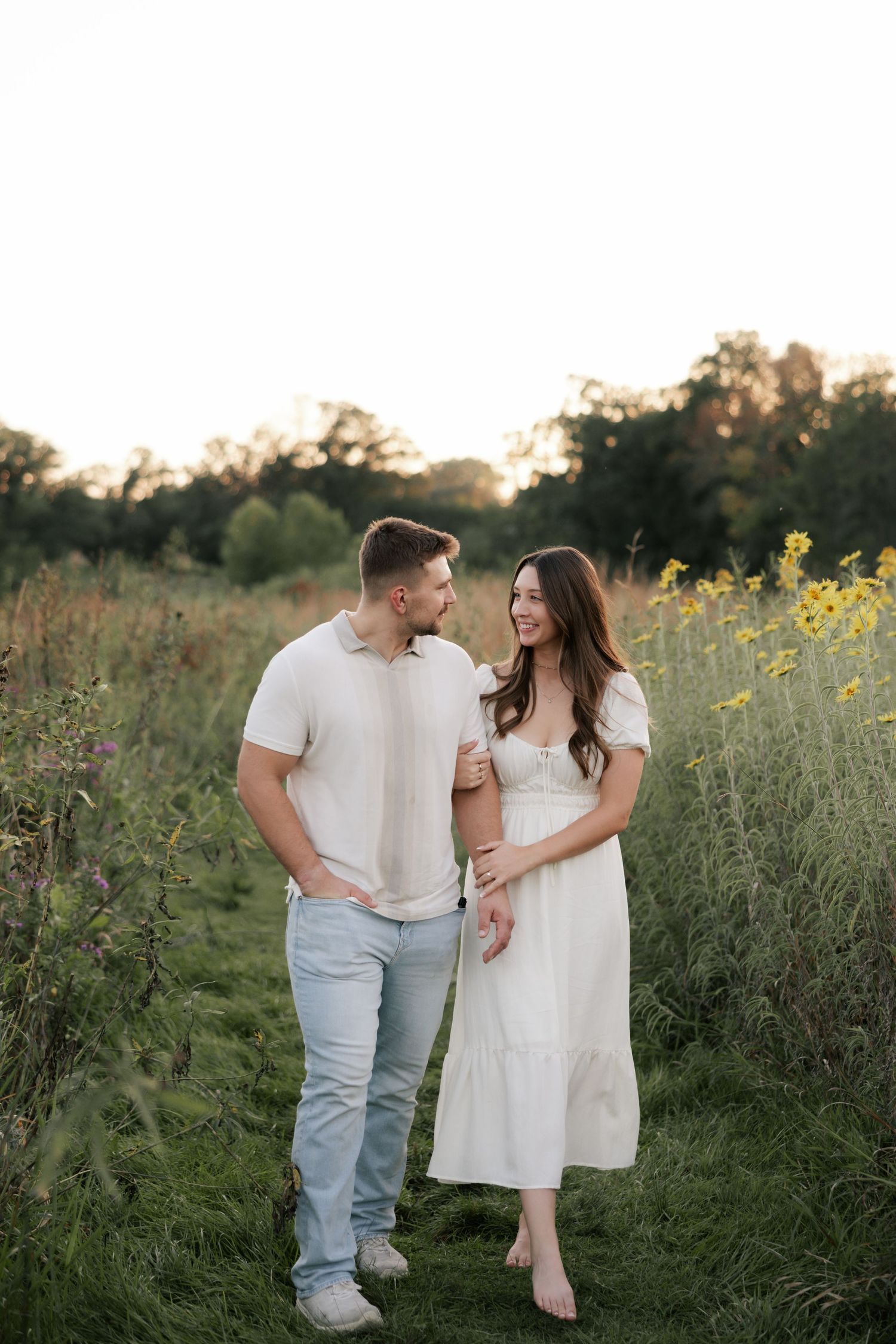 A couple shares a romantic moment together in a field of wildflowers during golden hour.