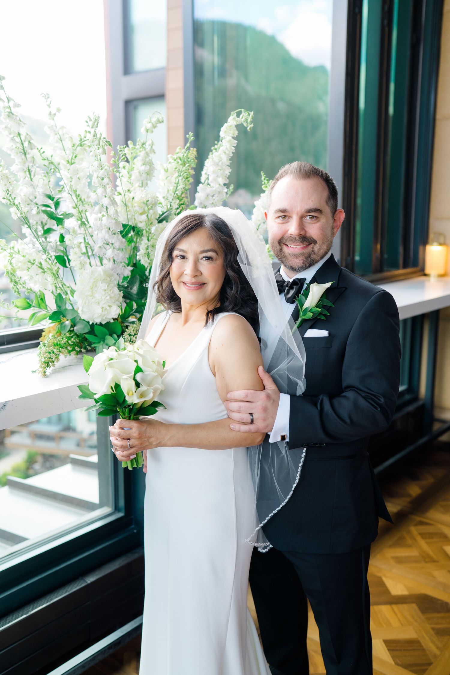 Elegant wedding couple dancing together in front of large windows in an indoor venue captured by vail wedding photographer.