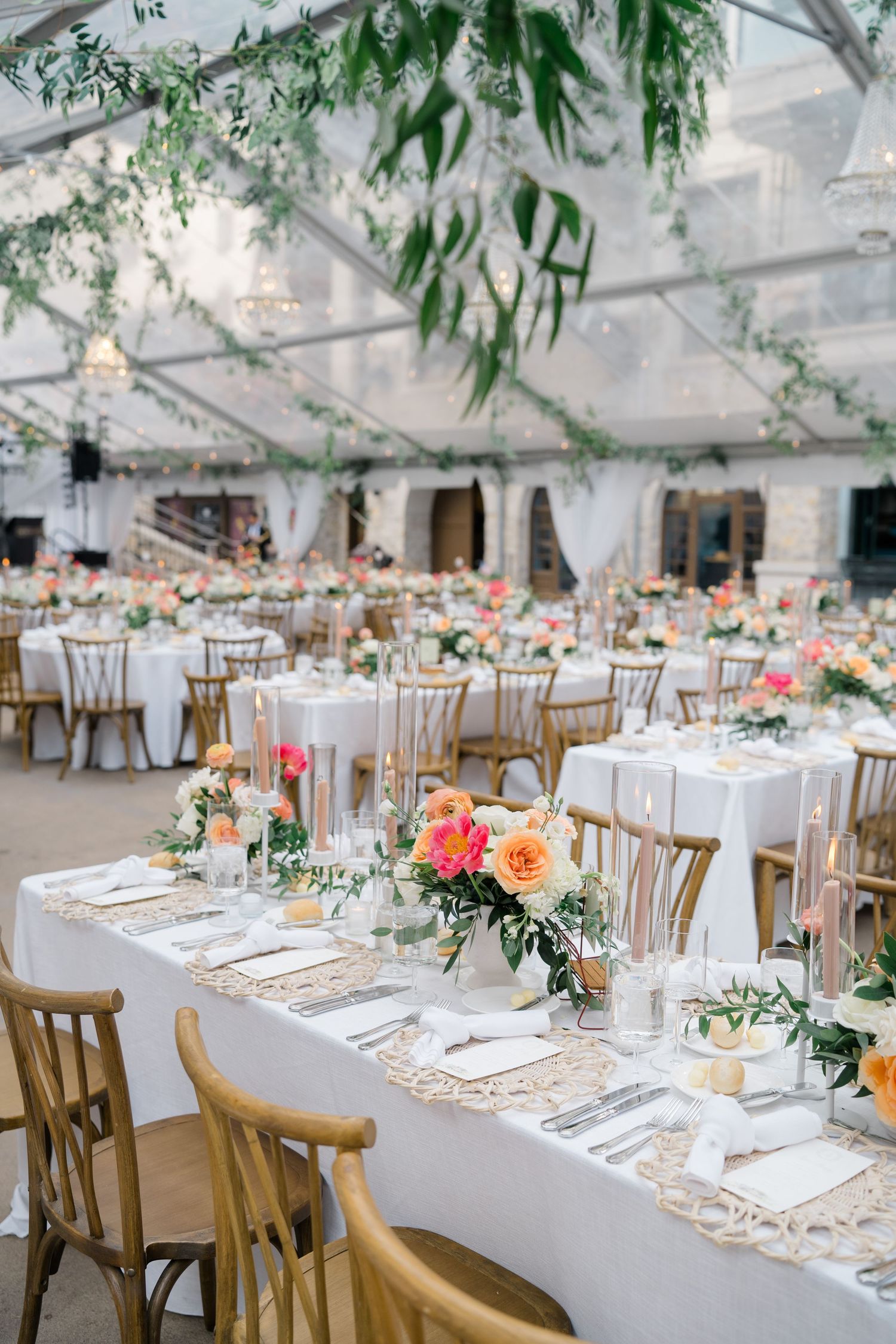 Elegant wedding reception tables set with white linens, wooden chairs and coral floral centerpieces  by Breckenridge wedding photographer.