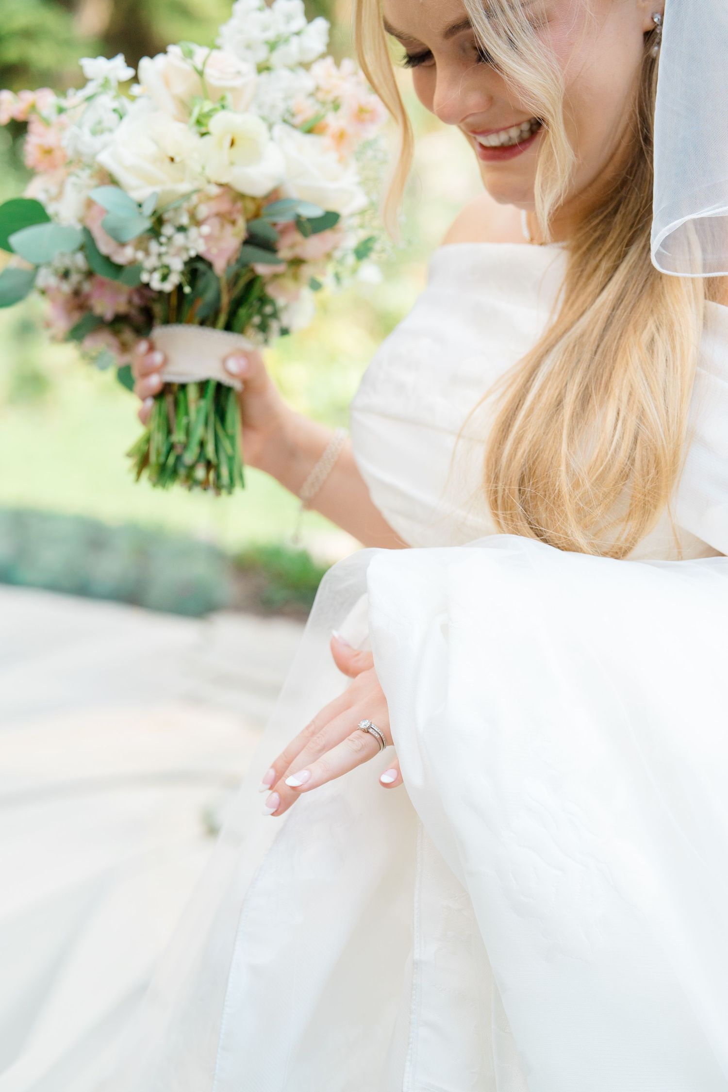 Close up details of a white wedding dress and delicate pastel floral bouquet.