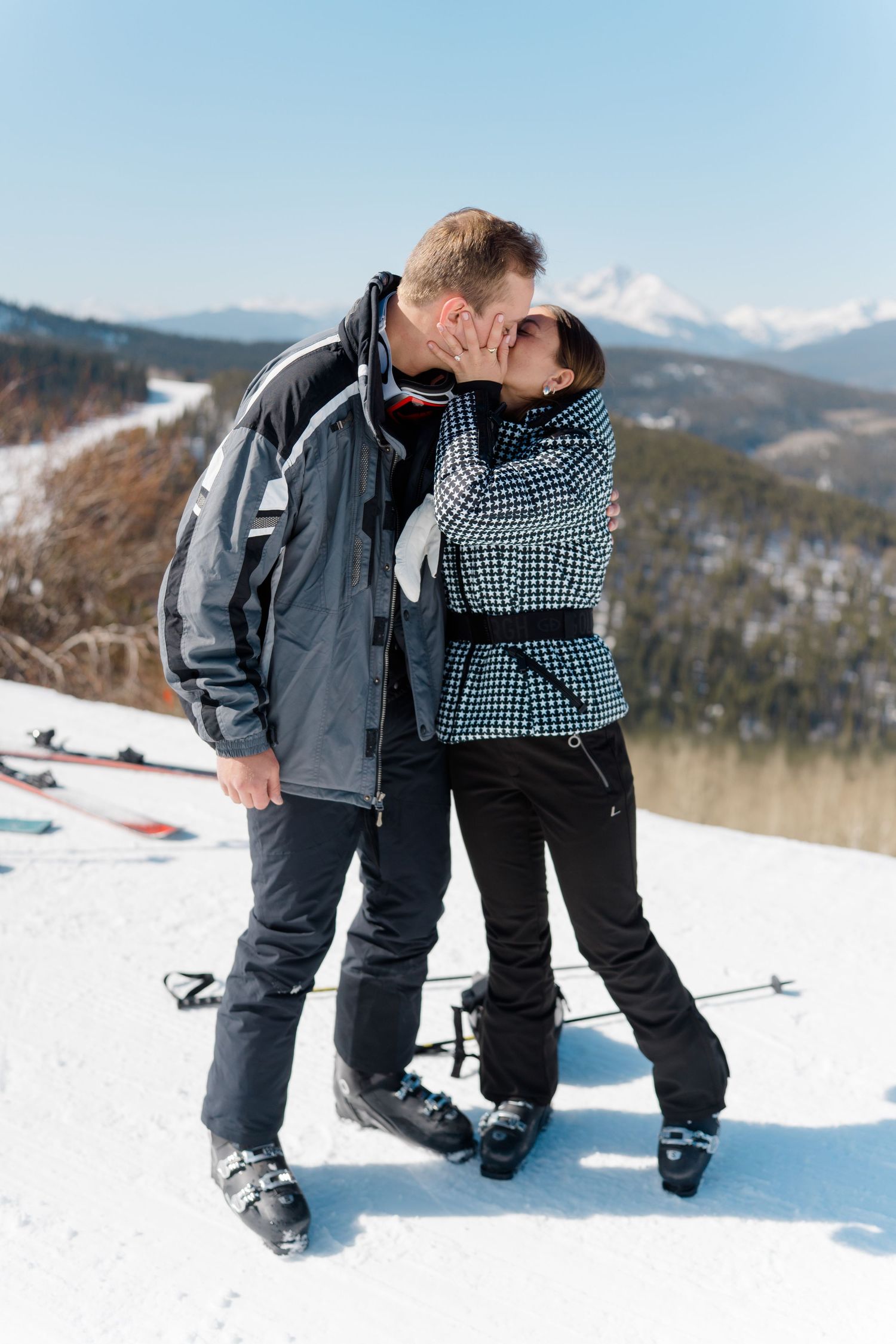 Two people share playful moments while skiing on a snow-covered mountain slope.