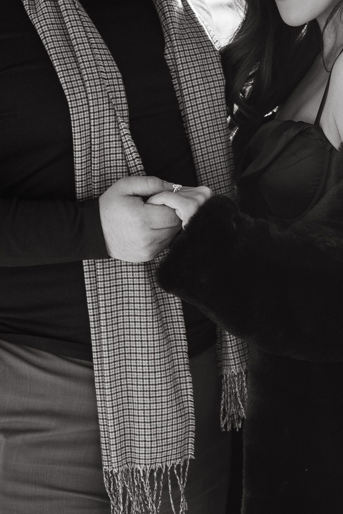 A series of black and white photos showing hands tying a checkered scarf in different steps.