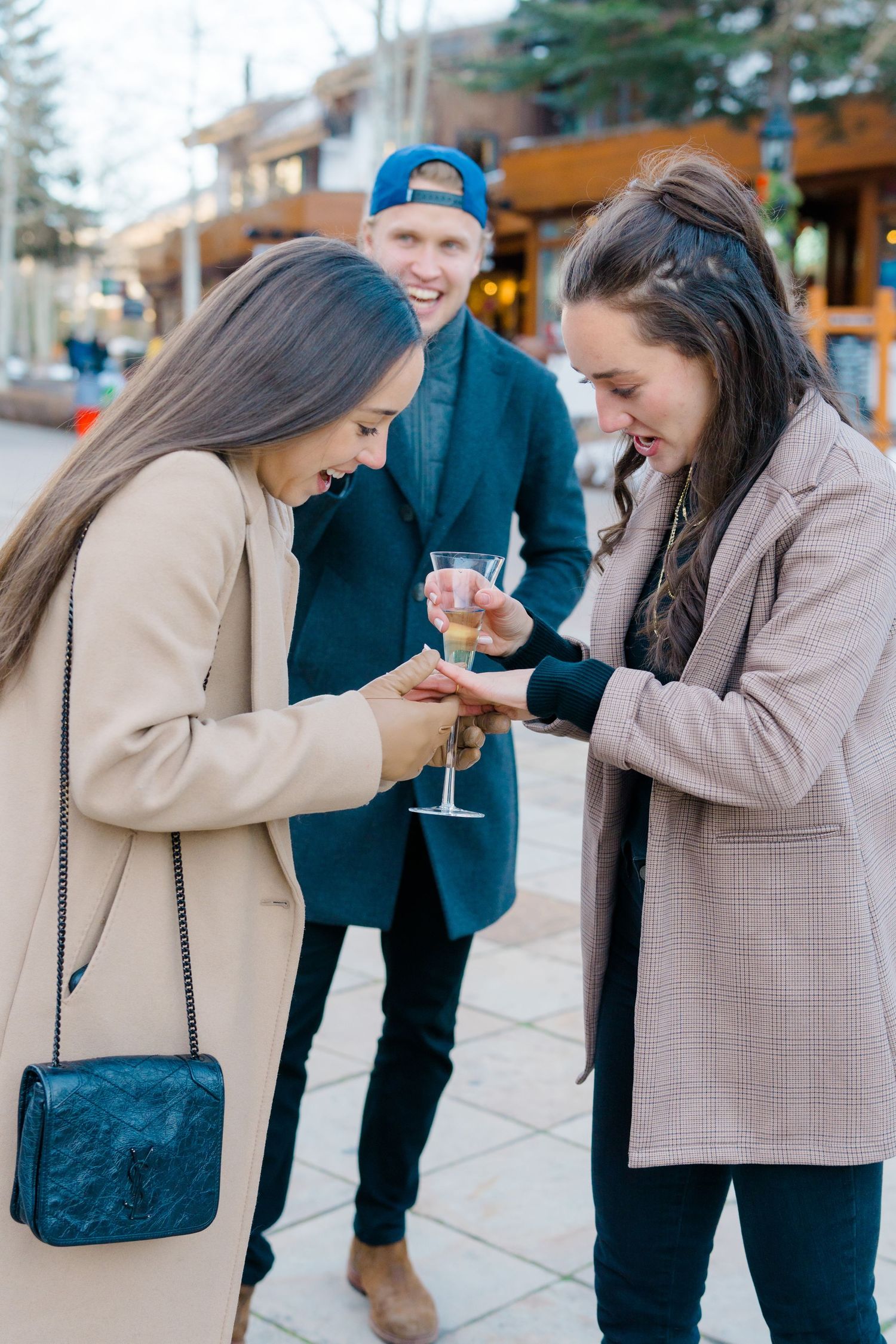 A couple shares a sweet moment while looking at something on a phone during a winter day in the city.