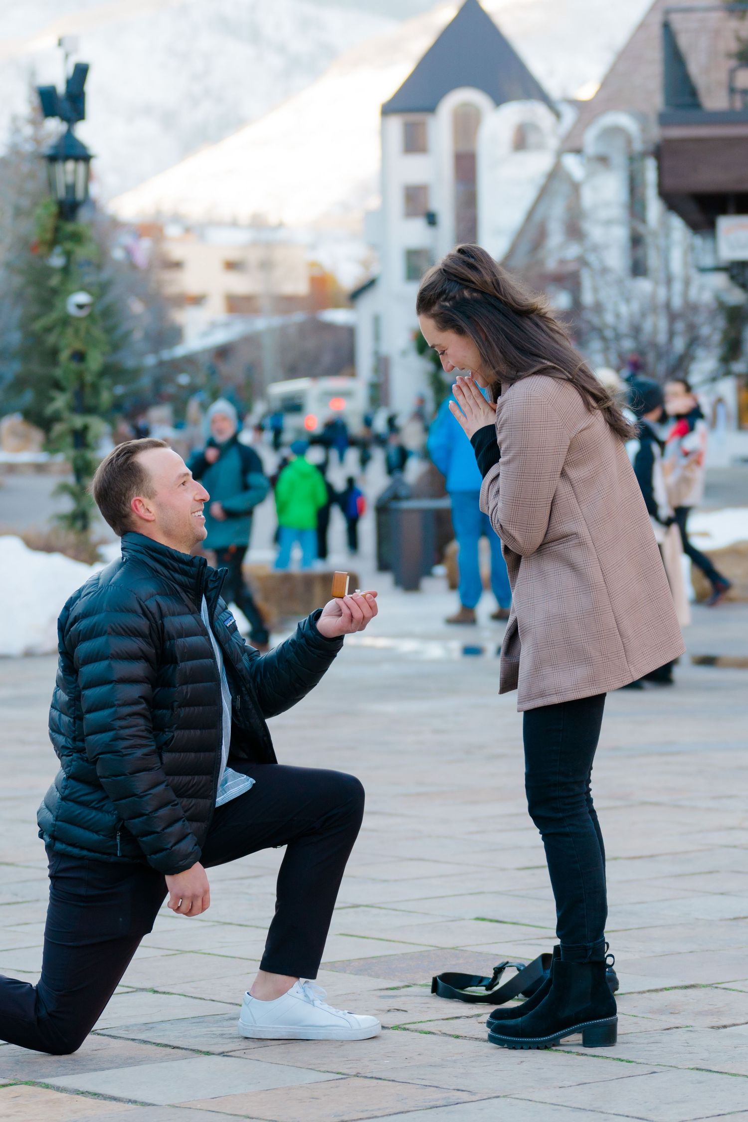 A romantic marriage proposal scene in front of a castle with onlookers in the background.