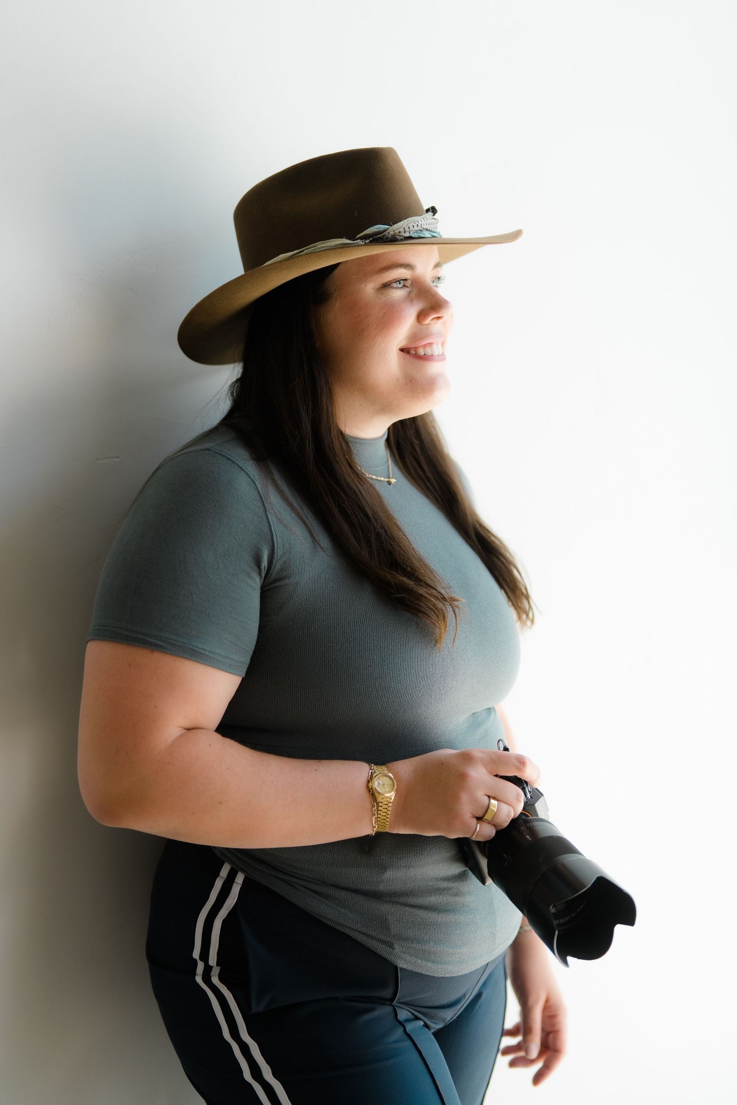 Breckenridge Wedding Photographer in brown hat and gray shirt holding professional camera against white background.