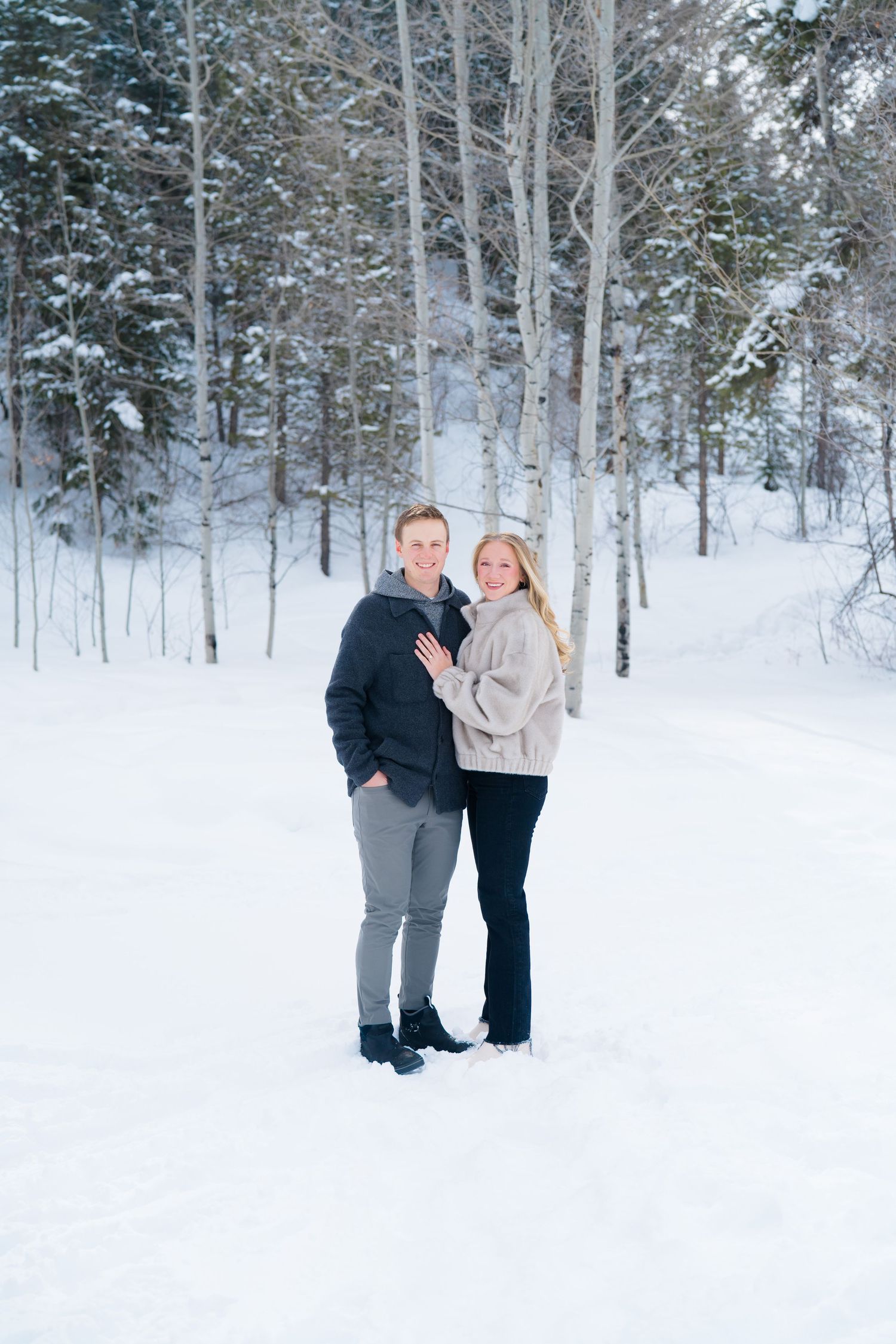 classic photo of guy and girl standing in snow looking at the camera with arms around each other