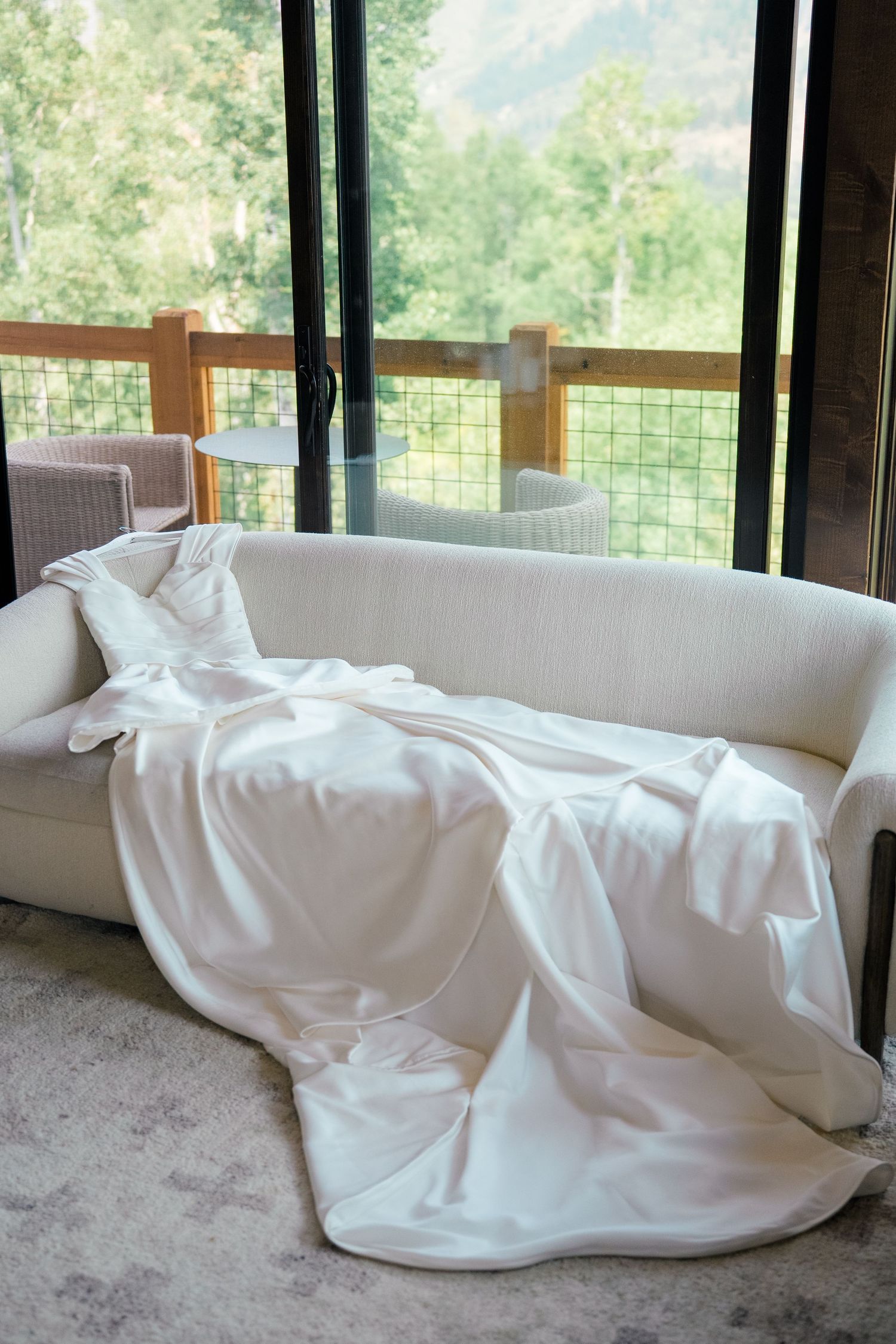 White fabric drapes elegantly across furniture near large windows overlooking a scenic mountain landscape.